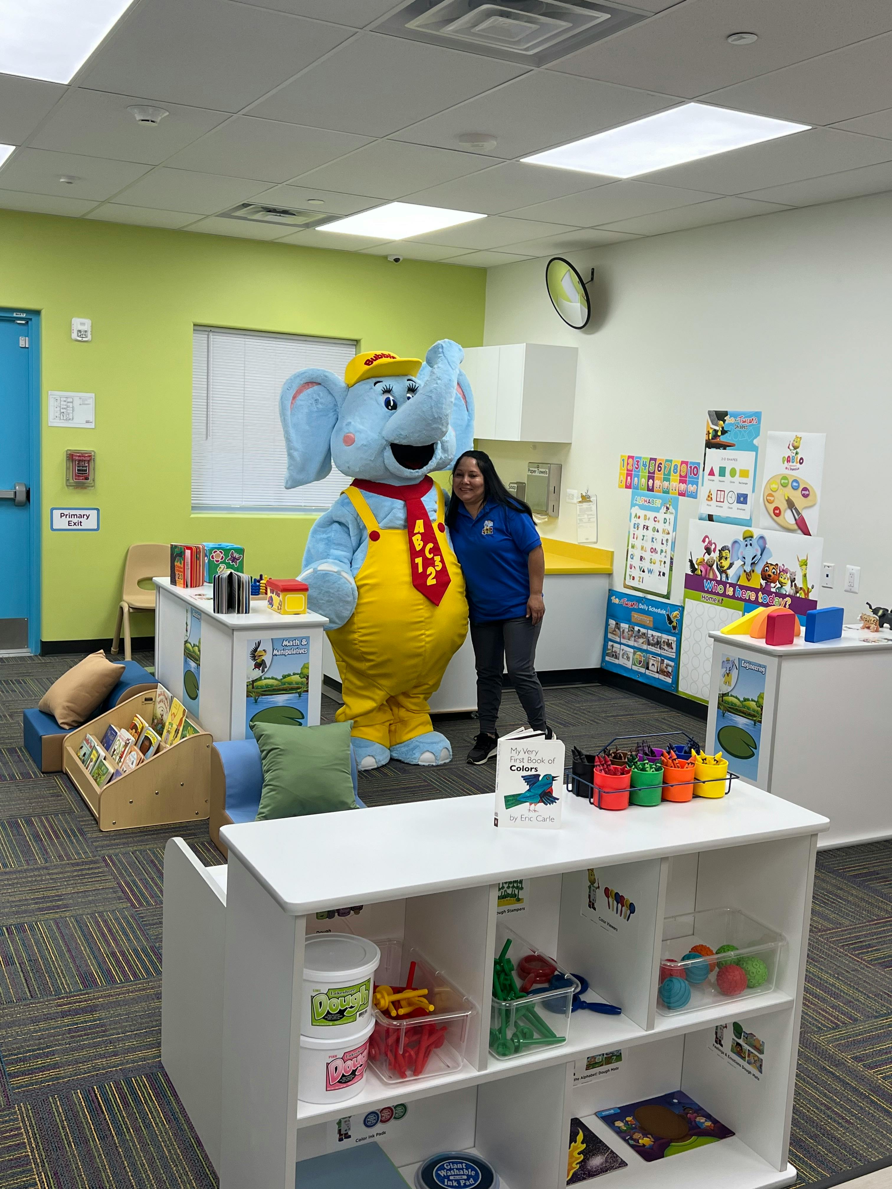 Person in an elephant mascot costume and another person standing in a classroom