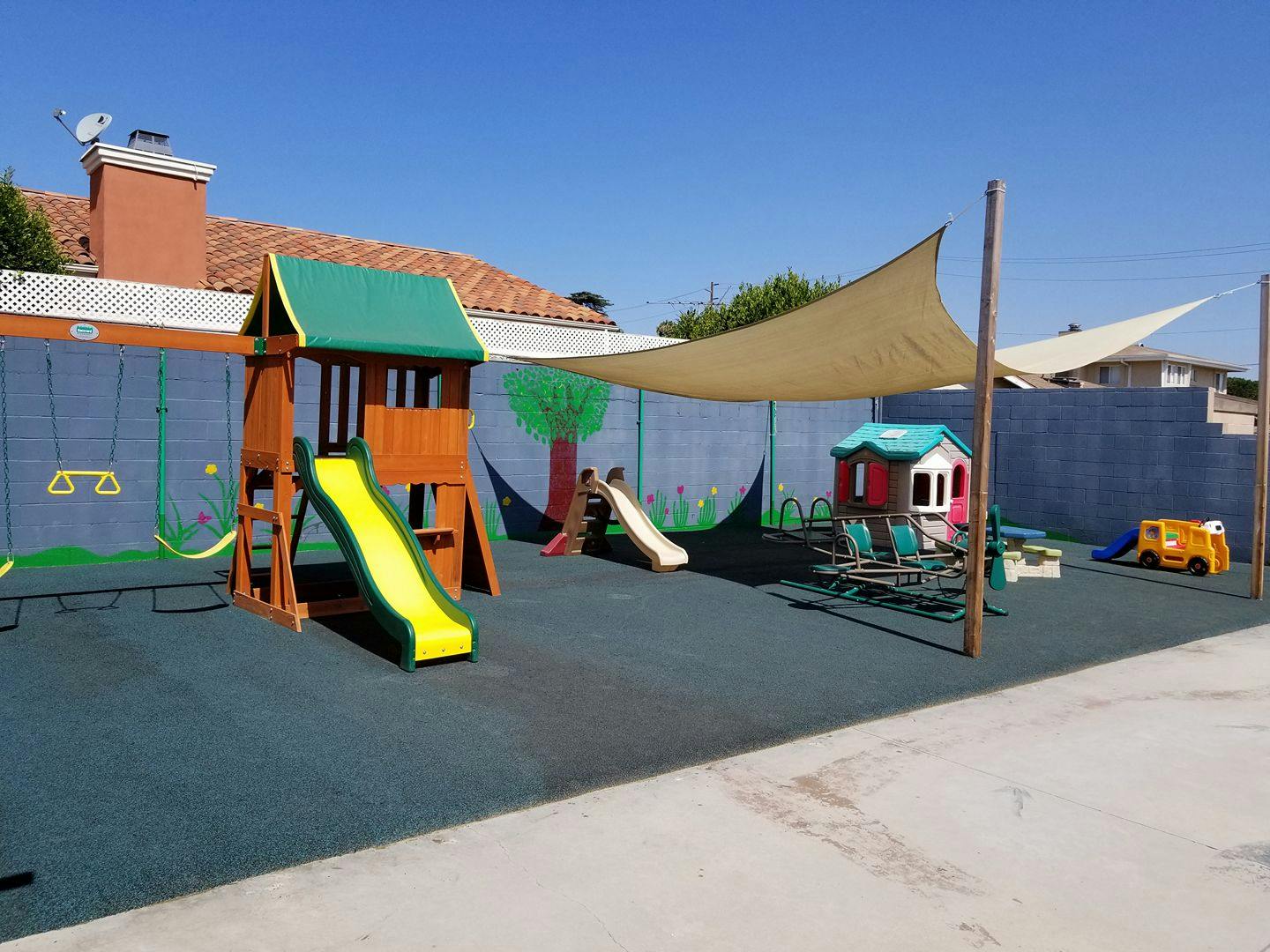 Outdoor playground with slides, swings, and playhouses on a rubber surface