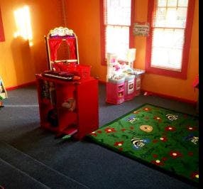 Children's play area with red toy kitchen and green rug