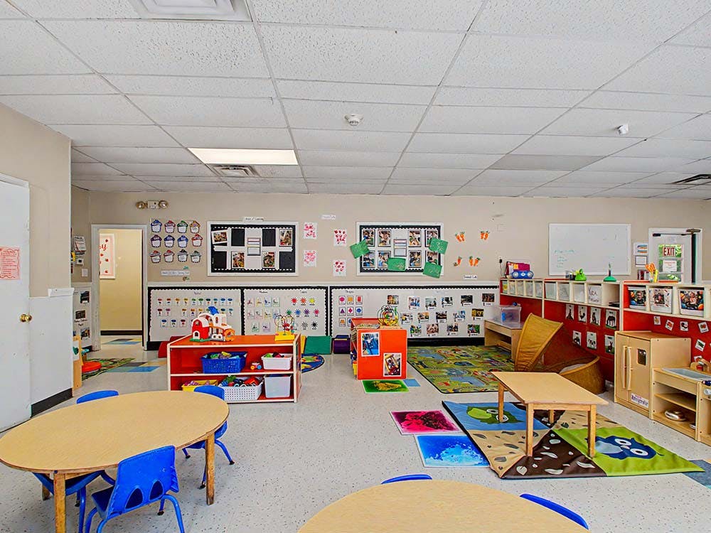 Classroom with tables, chairs, colorful rugs, and display boards