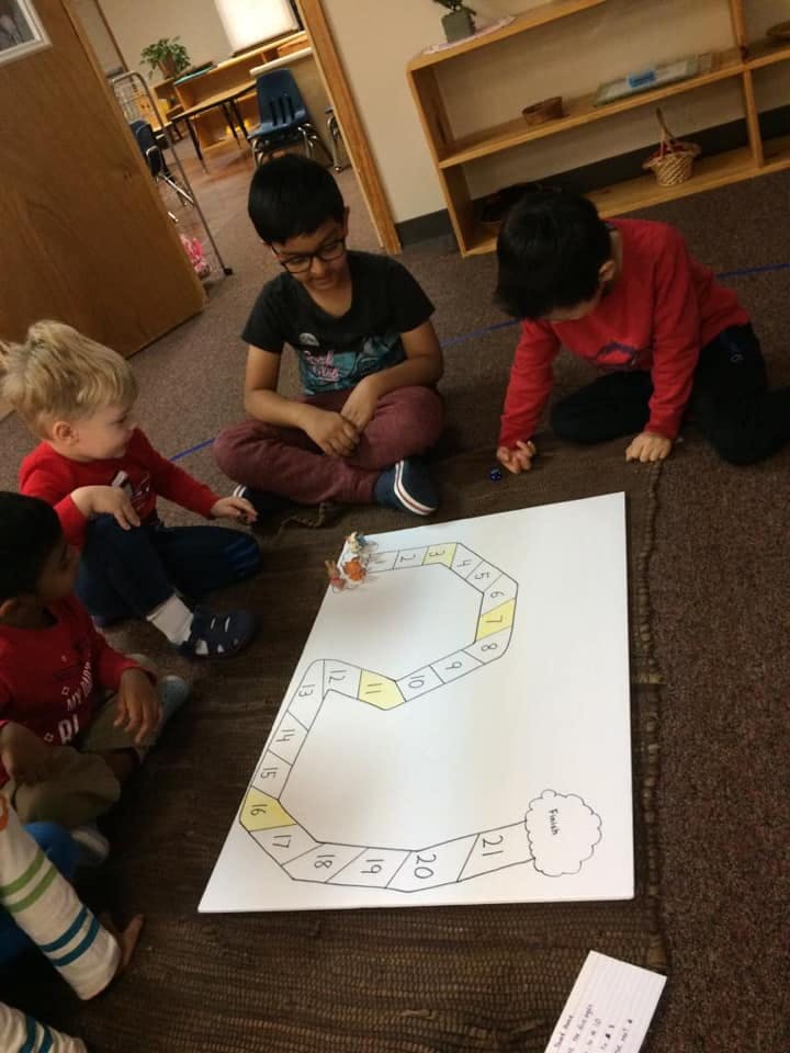 Four children playing a board game on the floor