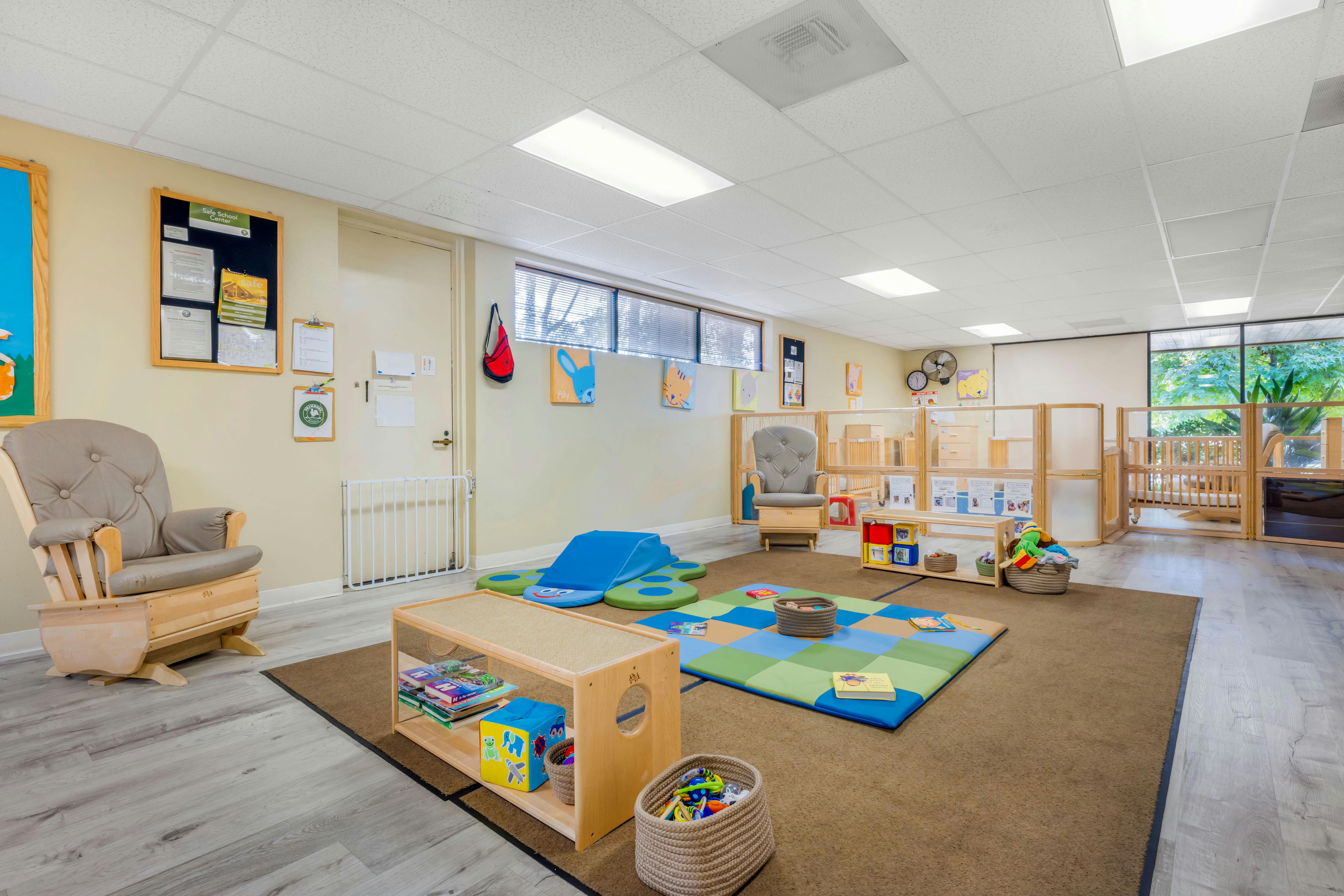 A playroom with a wooden rocker, a padded mat, and various children's toys