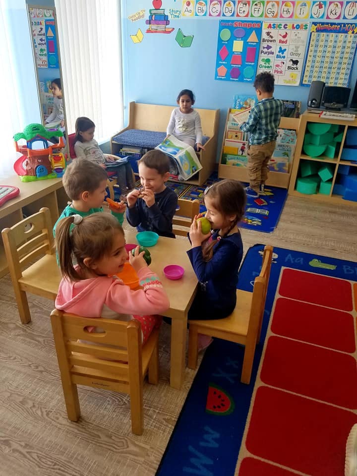 Children eating at a small table in a classroom