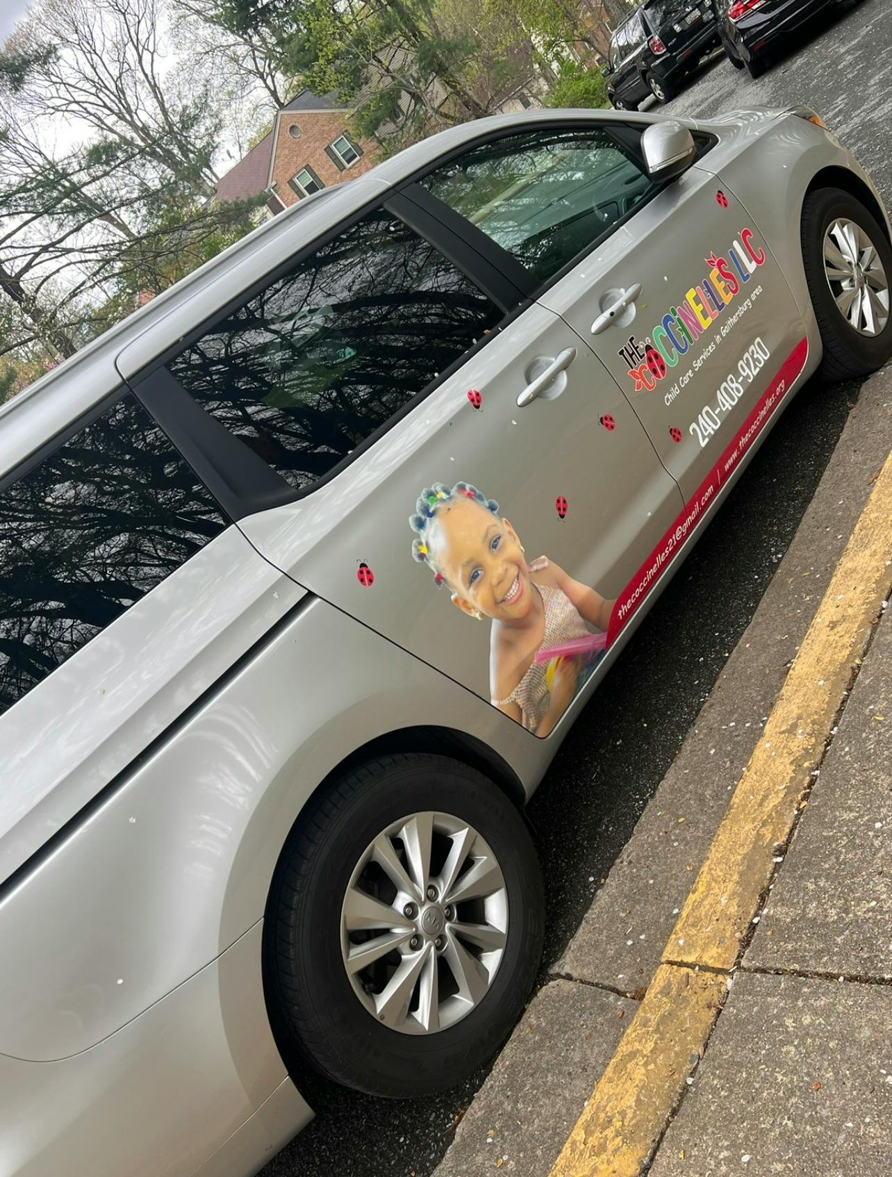 Side of a white van with a business logo featuring a child's face and ladybugs