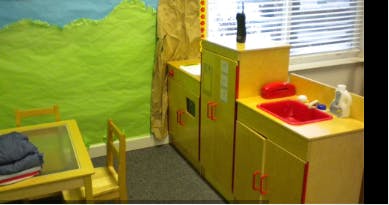 Play kitchen with red sink next to a small table and chair