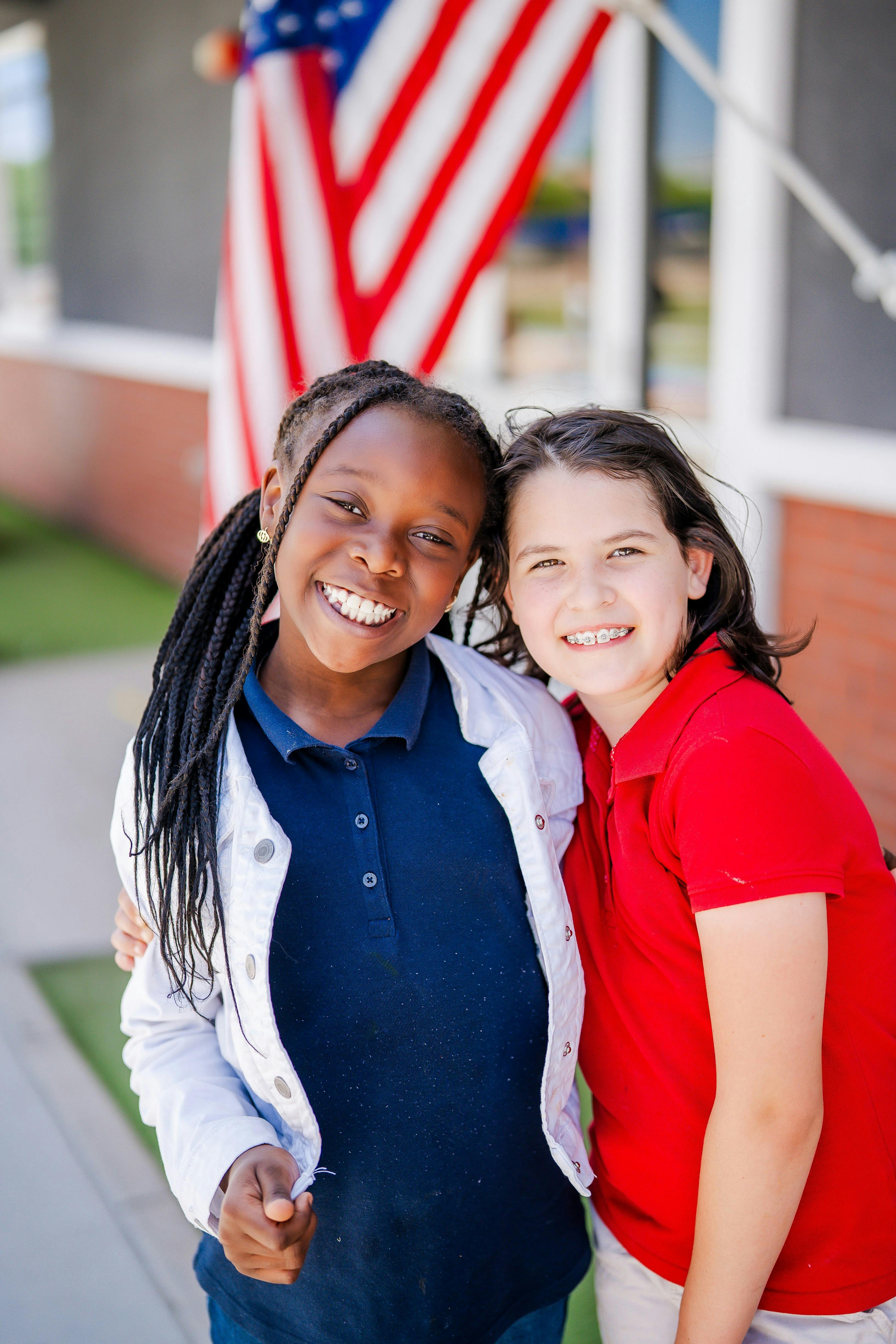 Two children smiling with an American flag in the background