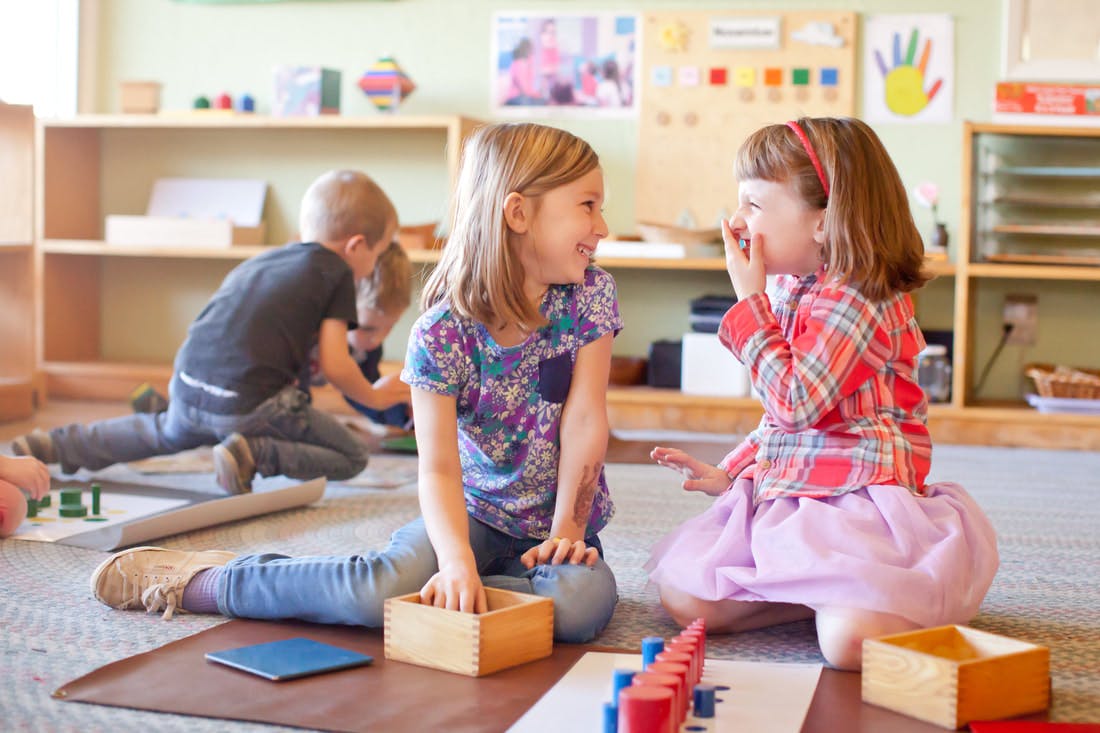 Two children playing on the floor in a classroom