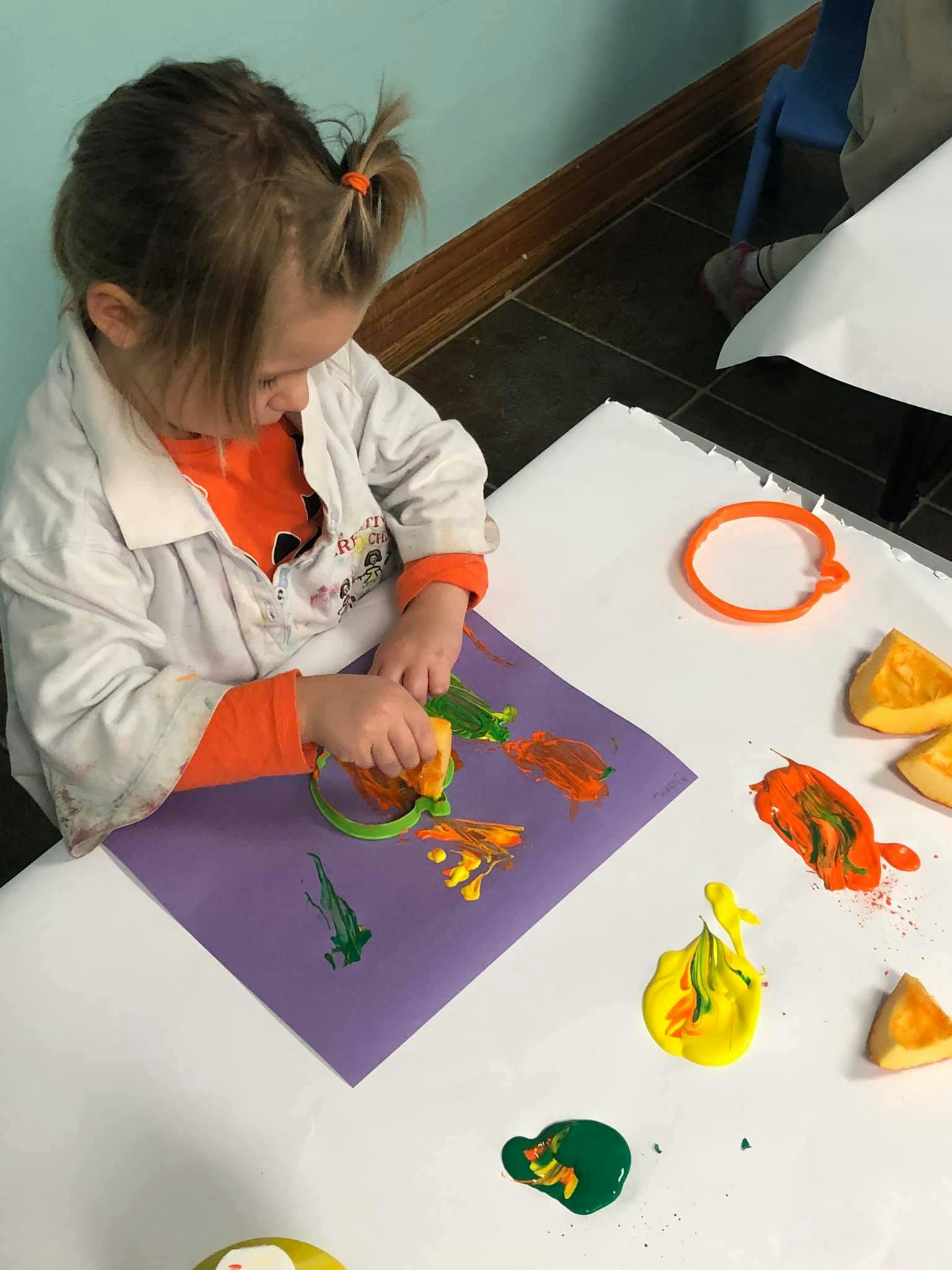 Child painting on purple paper with a sponge