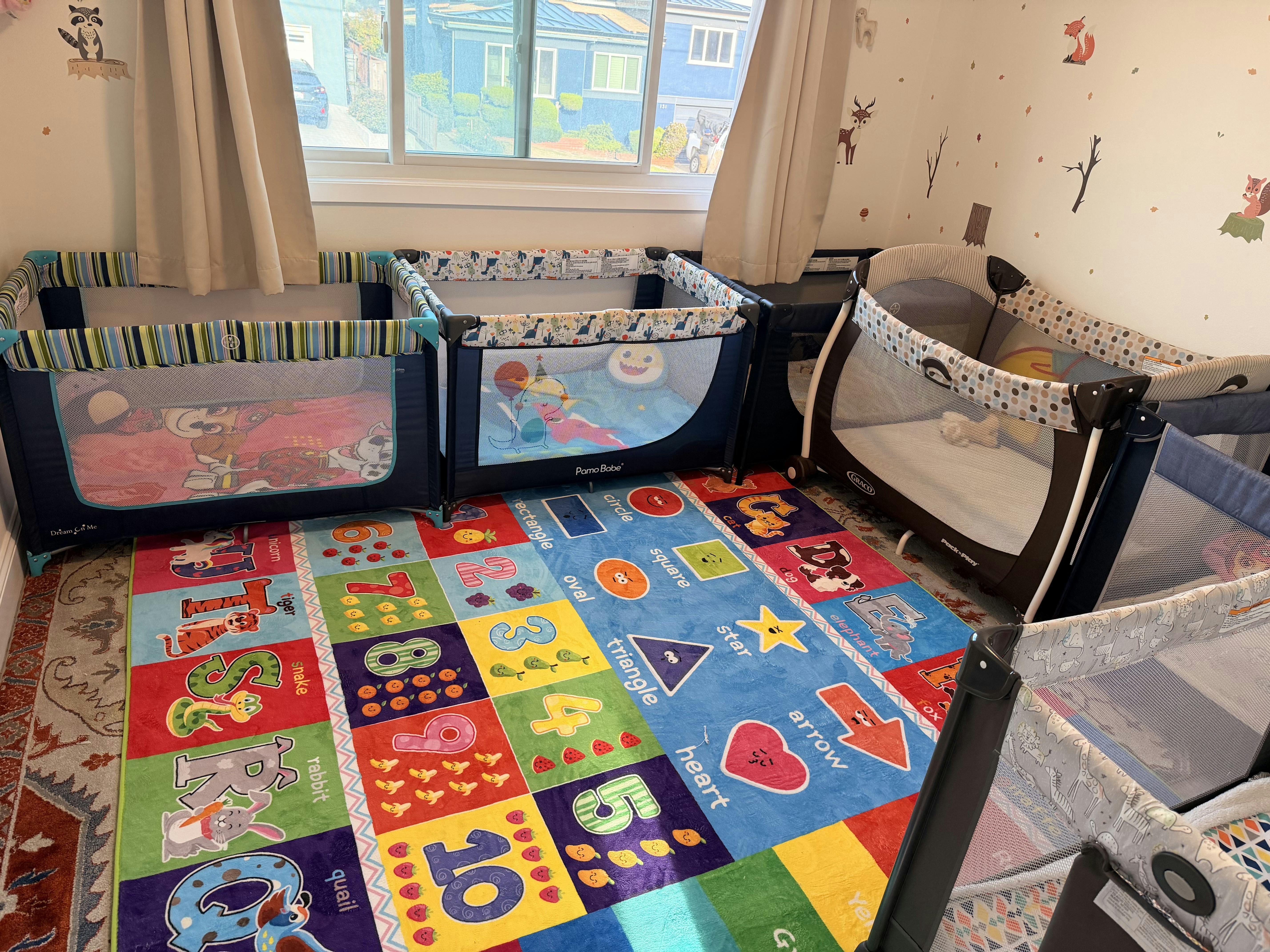Multiple playpens arranged on a colorful educational rug in a room