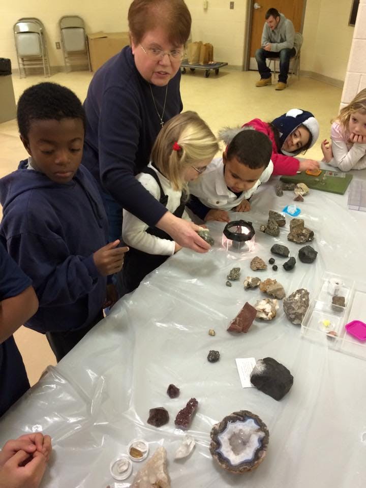 Adult and children examining rocks and minerals on a table