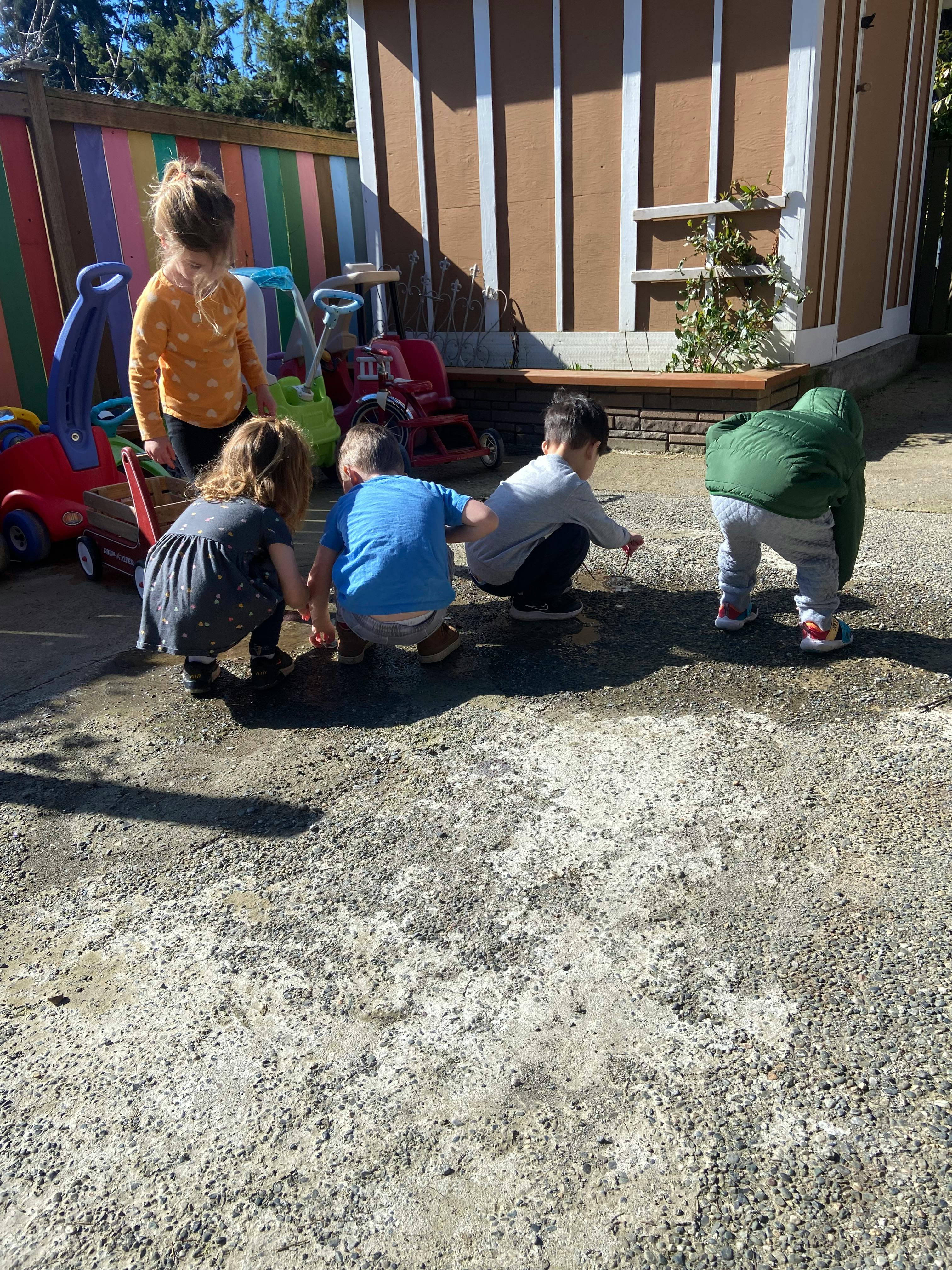 Four children playing on the ground outdoors