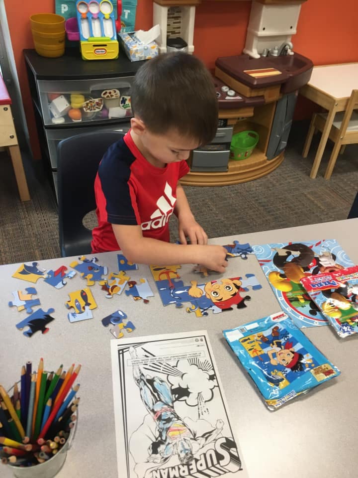 Child assembling a puzzle at a table