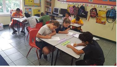 Children writing at desks in a classroom