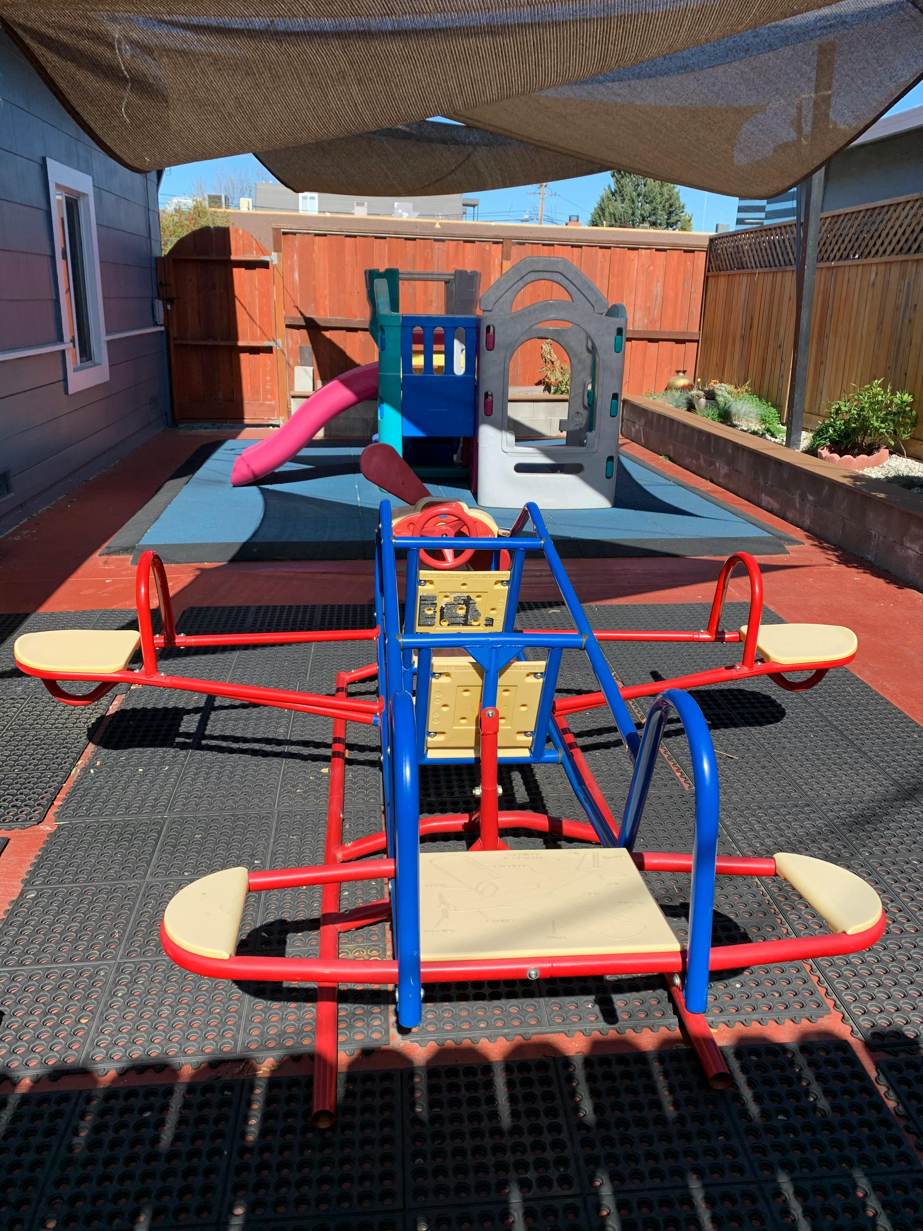 Playground with a red and blue seesaw and a play structure with a slide