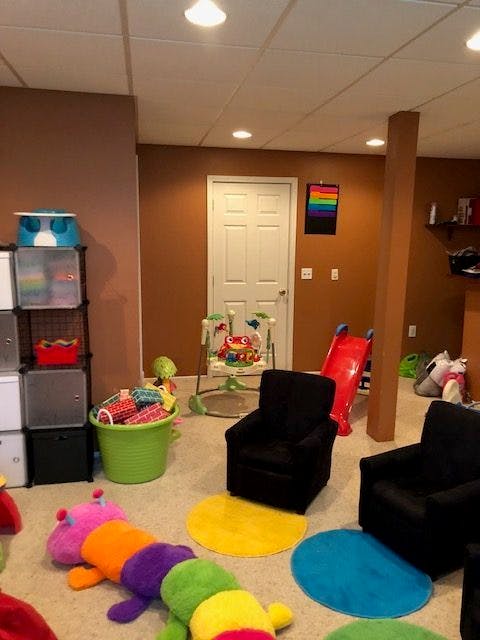 Playroom with a colorful caterpillar toy, chairs, and a baby bouncer