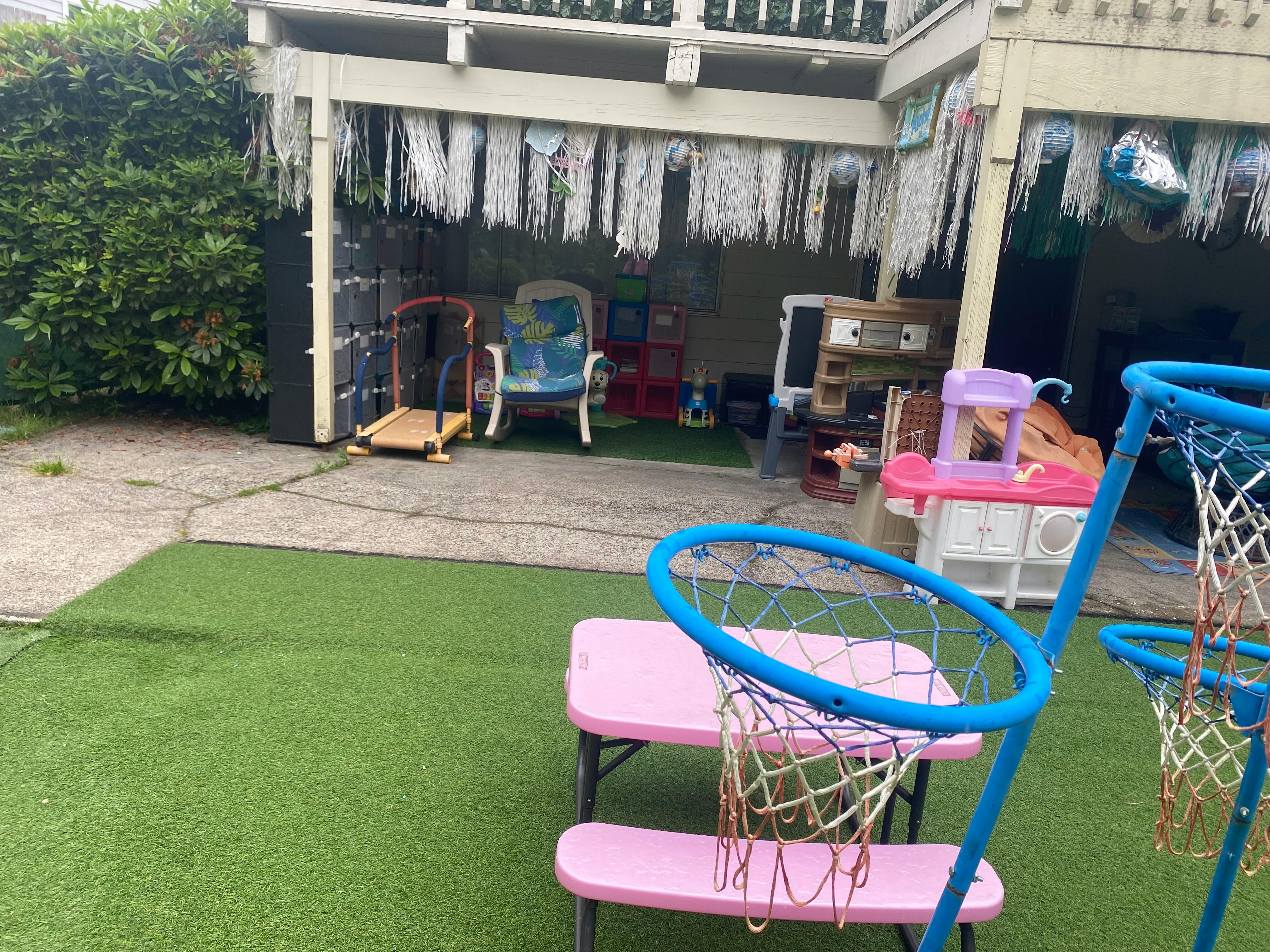 Play area with artificial turf, basketball hoops, and children's furniture