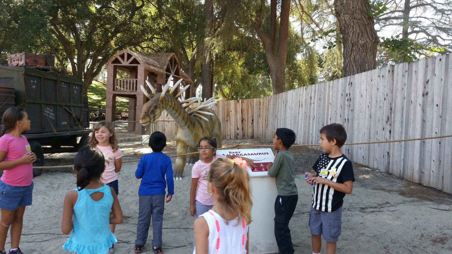 Children gathered around a dragon statue outdoors