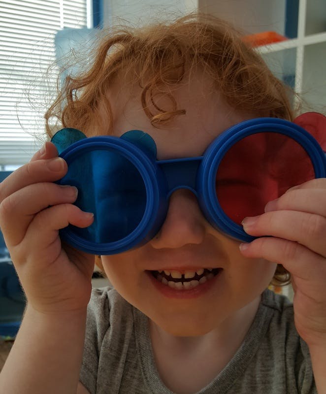 Child peeking over blue and red 3D glasses