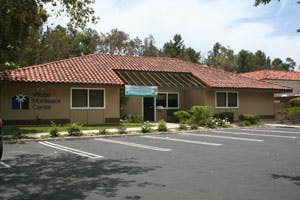 Building with a red tile roof and a parking lot in front