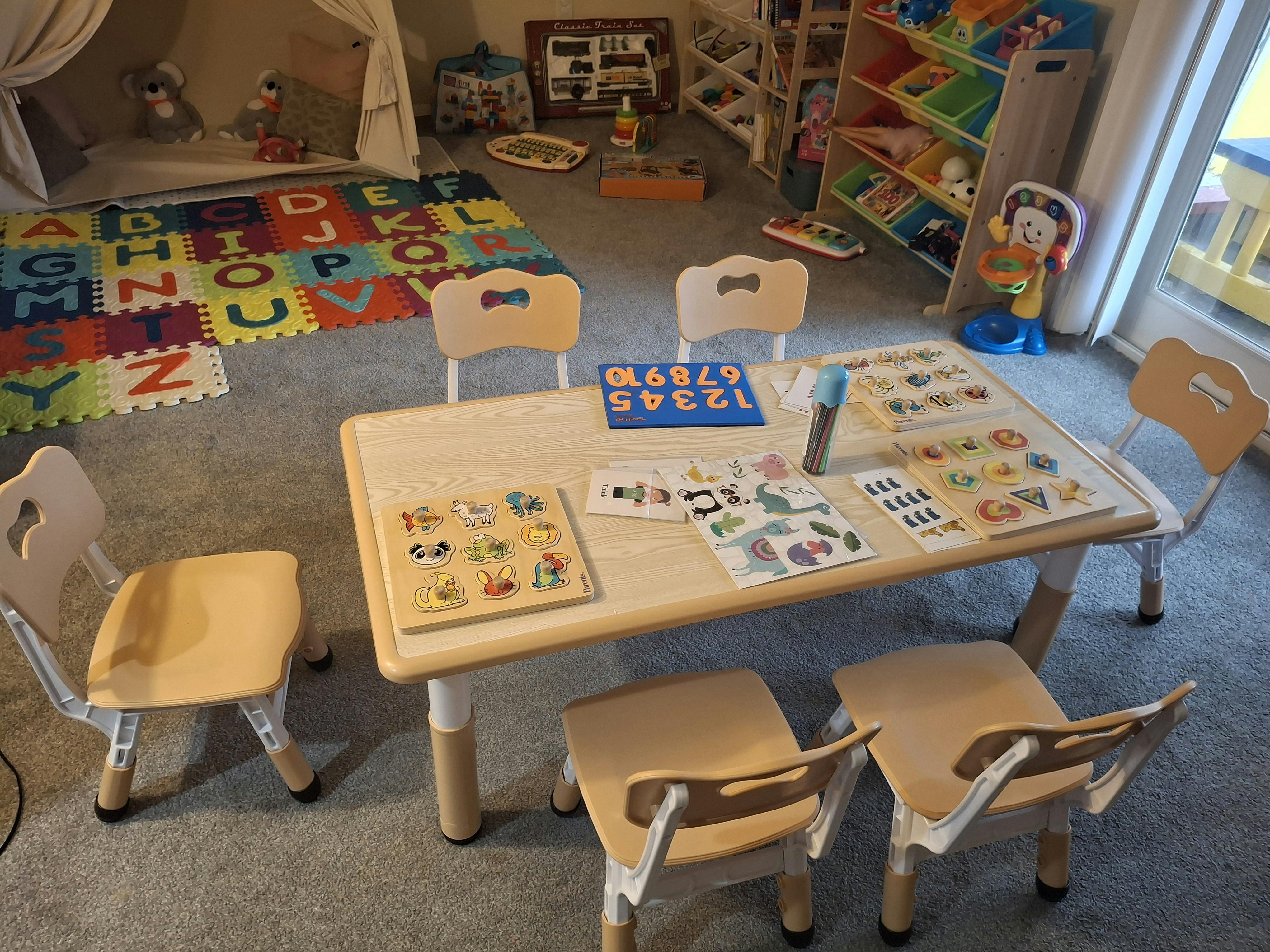 Playroom with a table and chairs surrounded by toys and an alphabet mat
