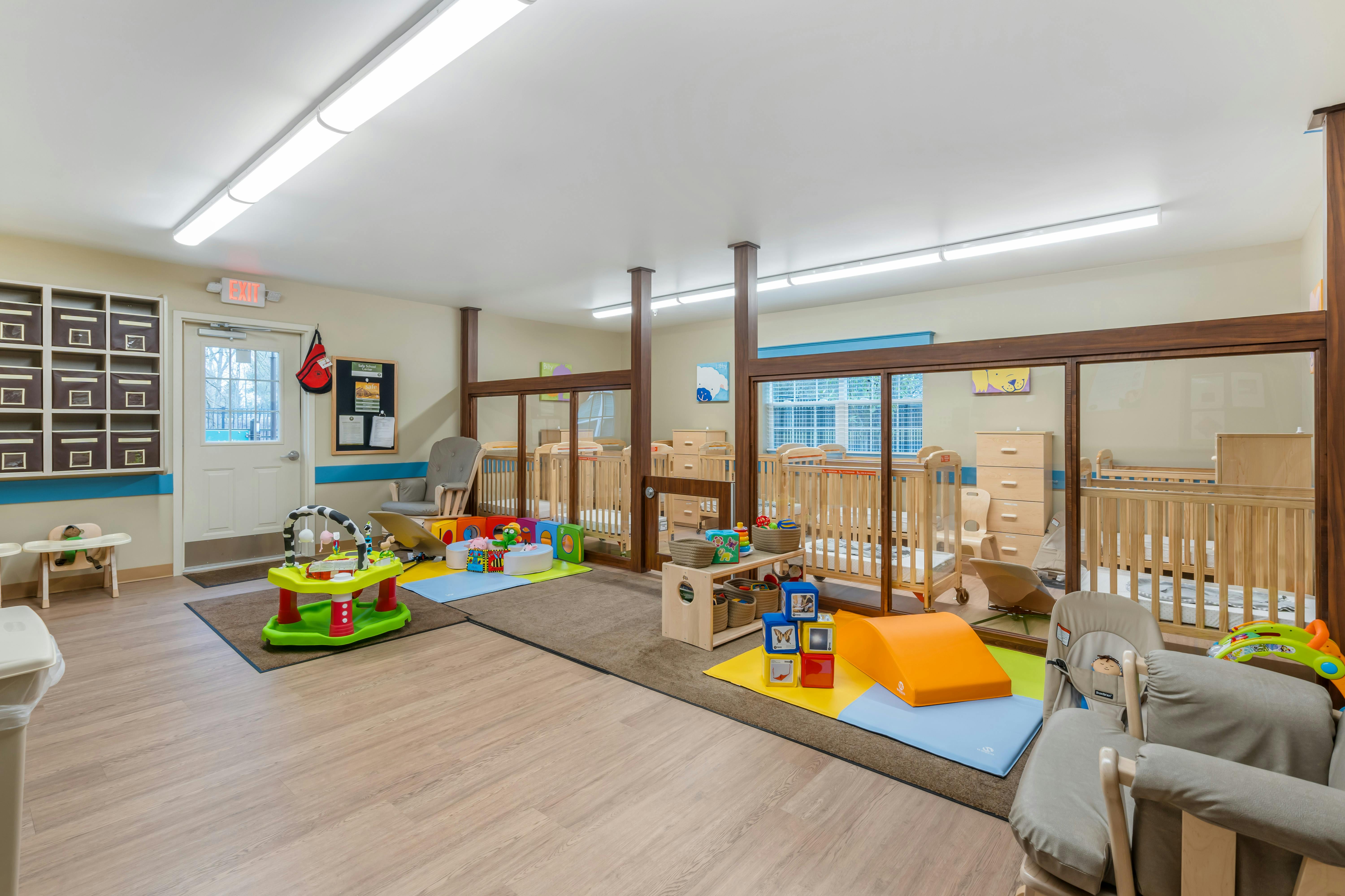 Baby daycare room with cribs, play mats, and toys