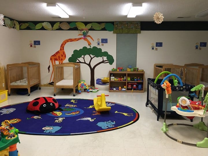 Nursery room with cribs, playmat, and wall decals