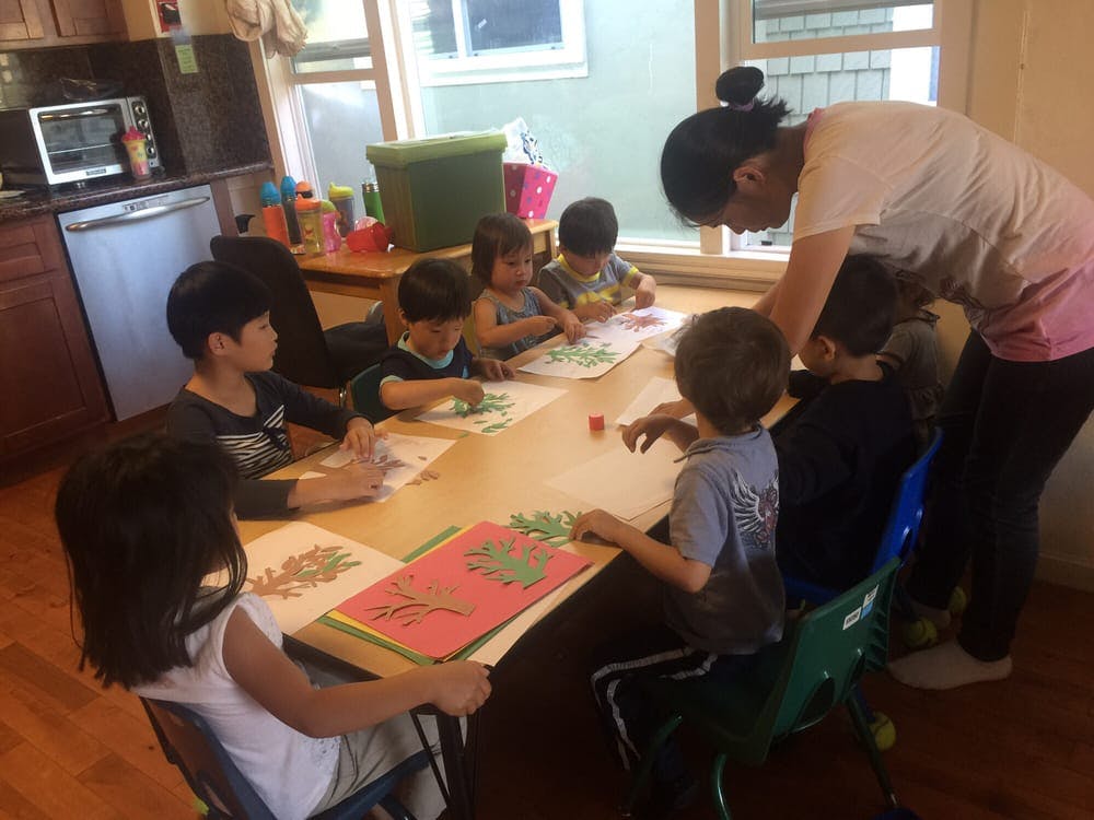 Adult supervising children doing crafts at a table