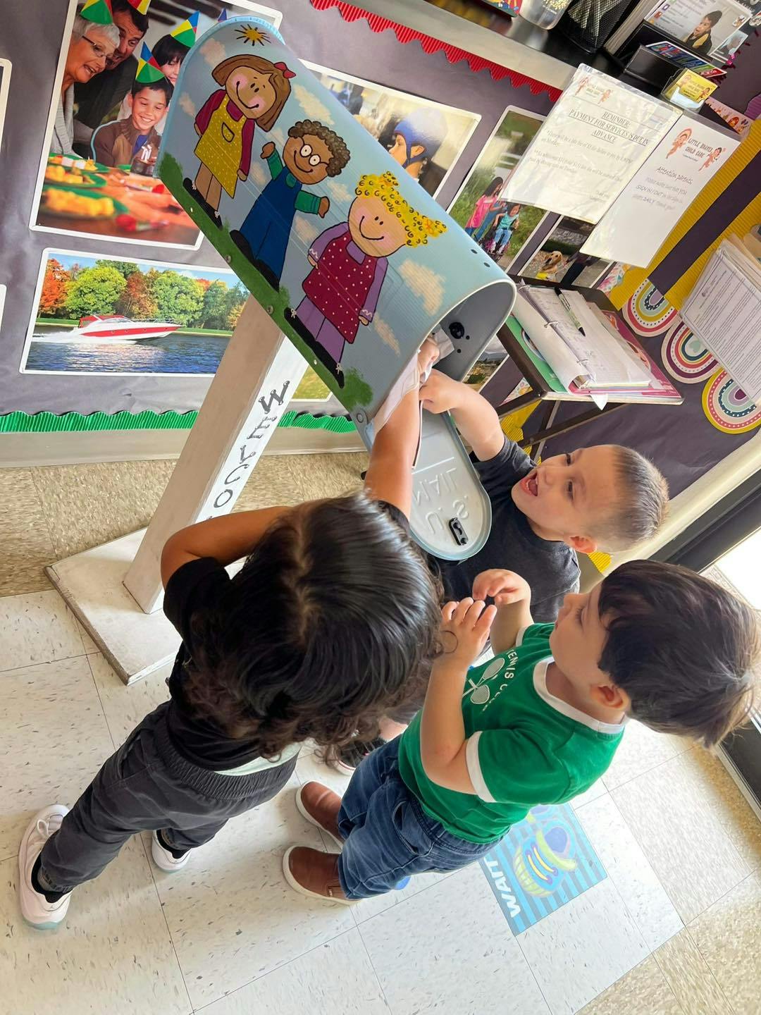 Three children playing with a toy mailbox