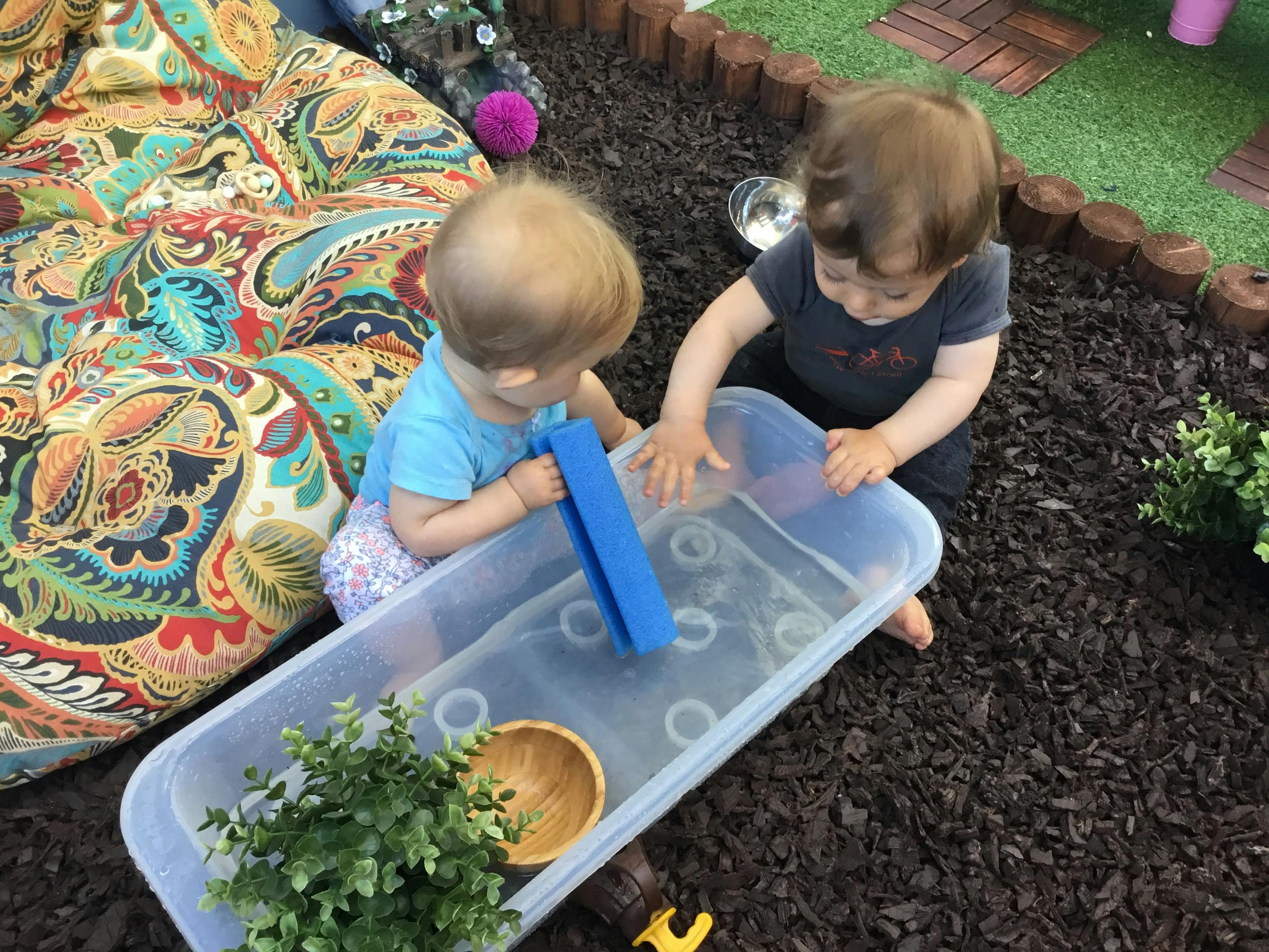 Two children playing with a plastic bin and toys