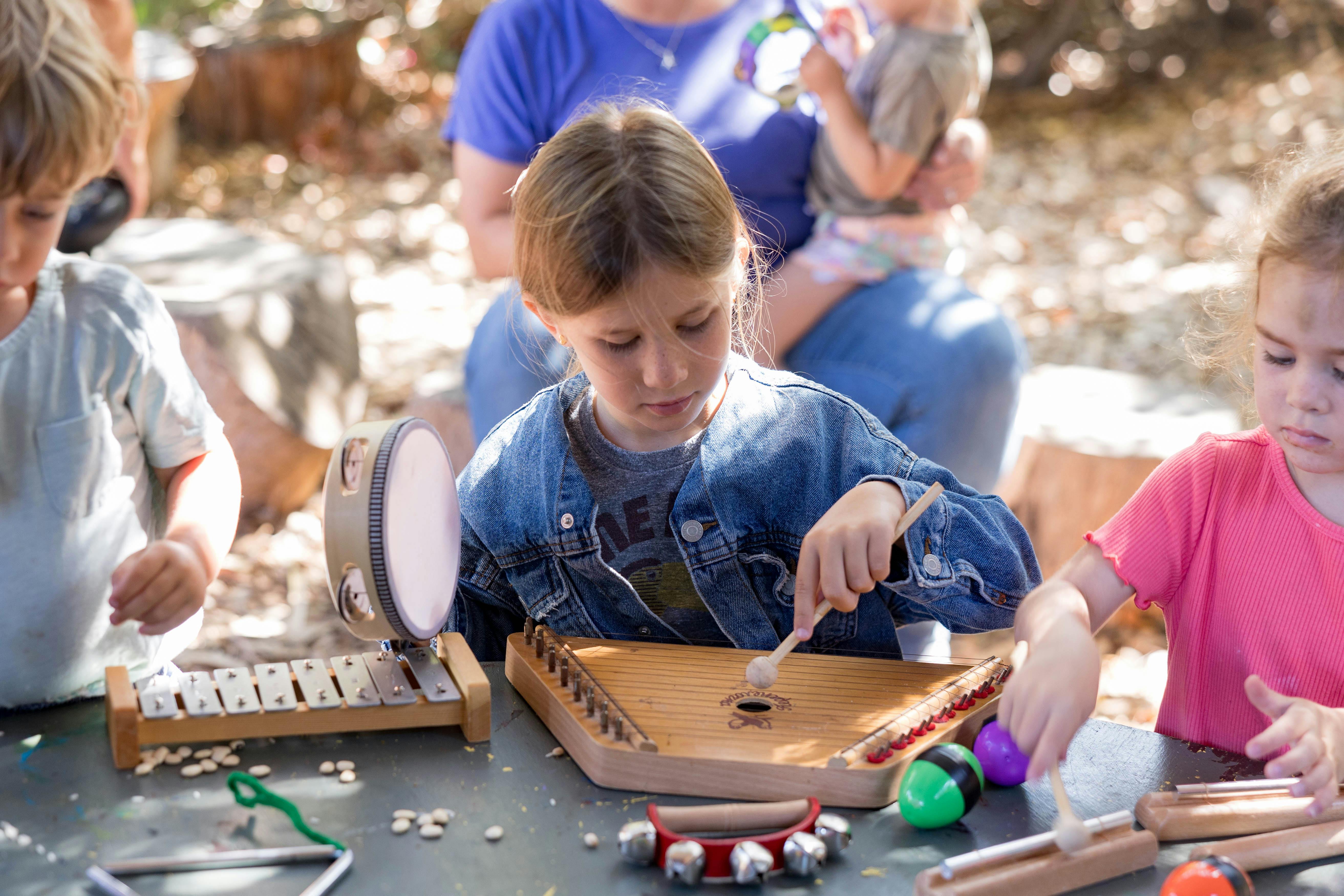 Child playing a musical instrument, surrounded by other children and instruments