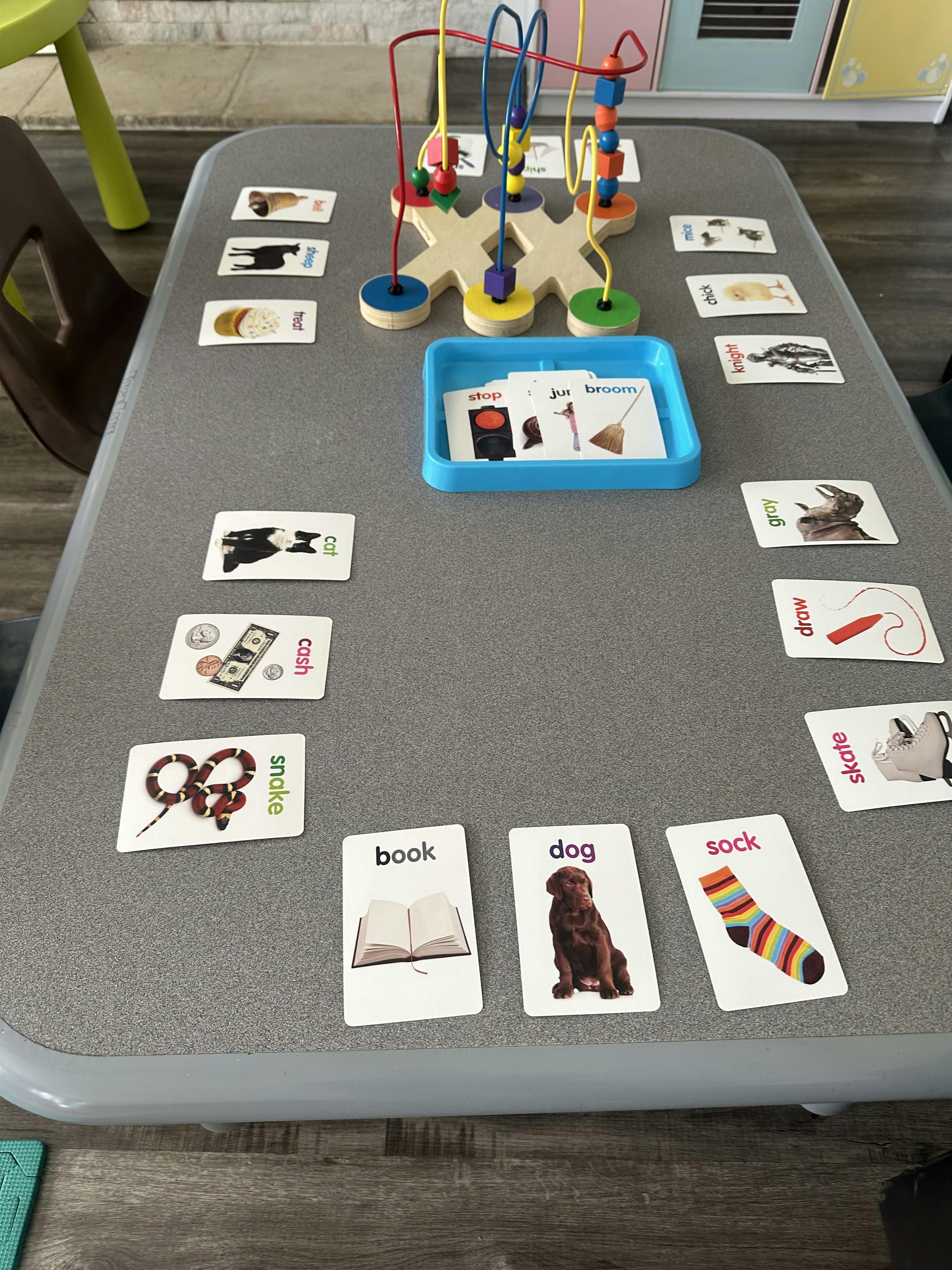 Table with a bead maze toy and flashcards spread around it