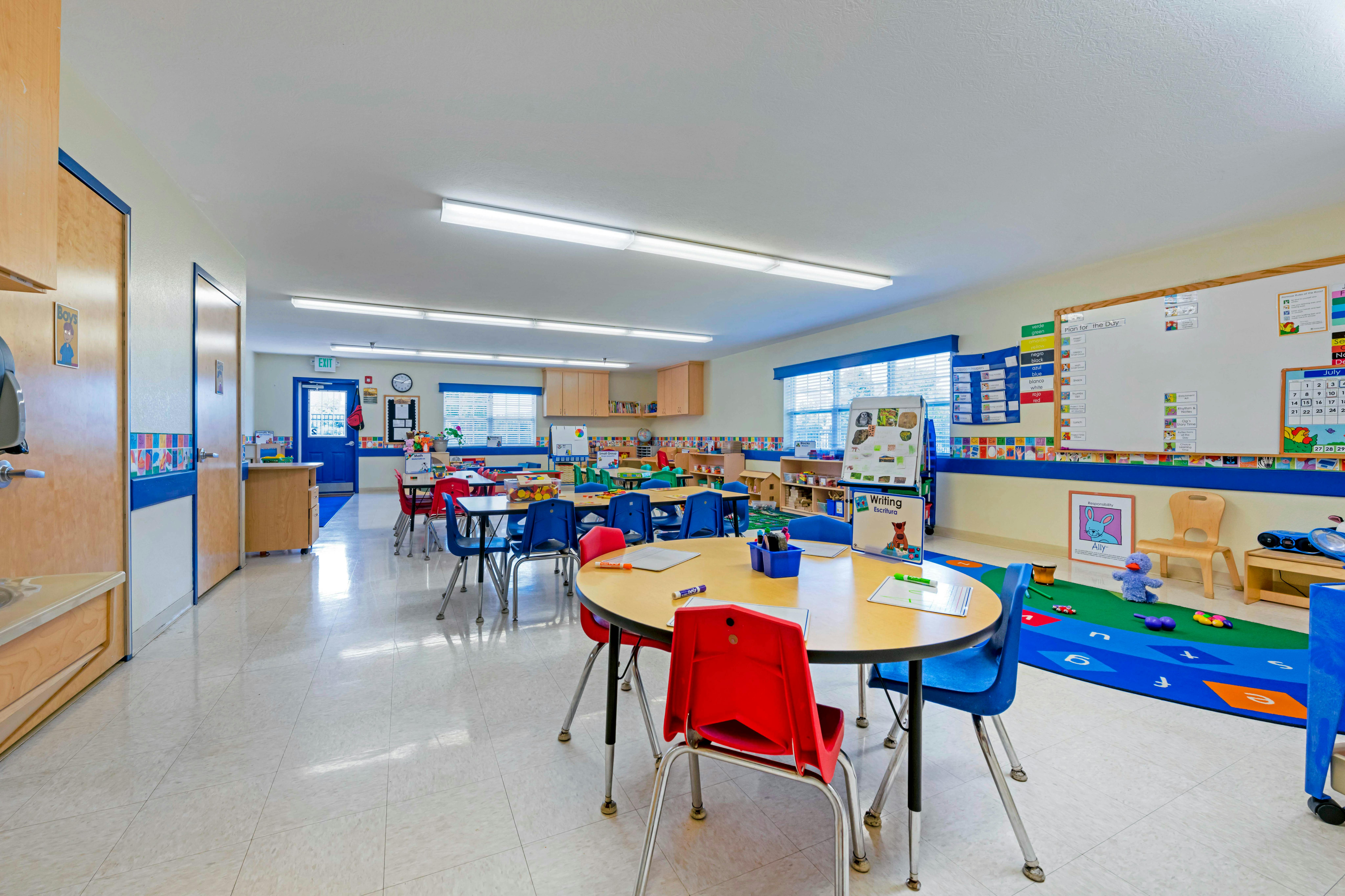 Classroom with small tables and chairs, whiteboards, and children's toys
