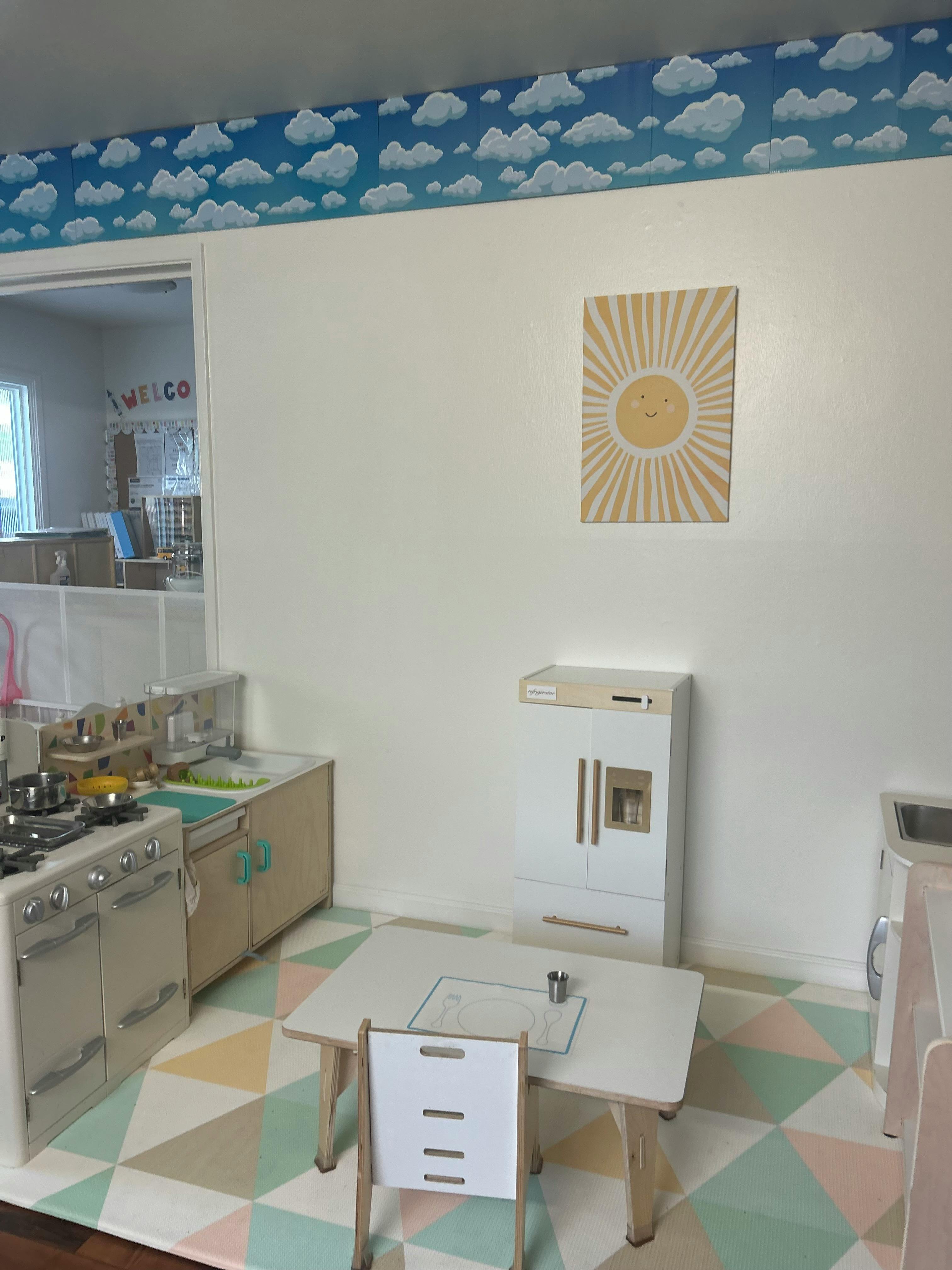 Play kitchen with stove, sink, refrigerator, and small table with chair