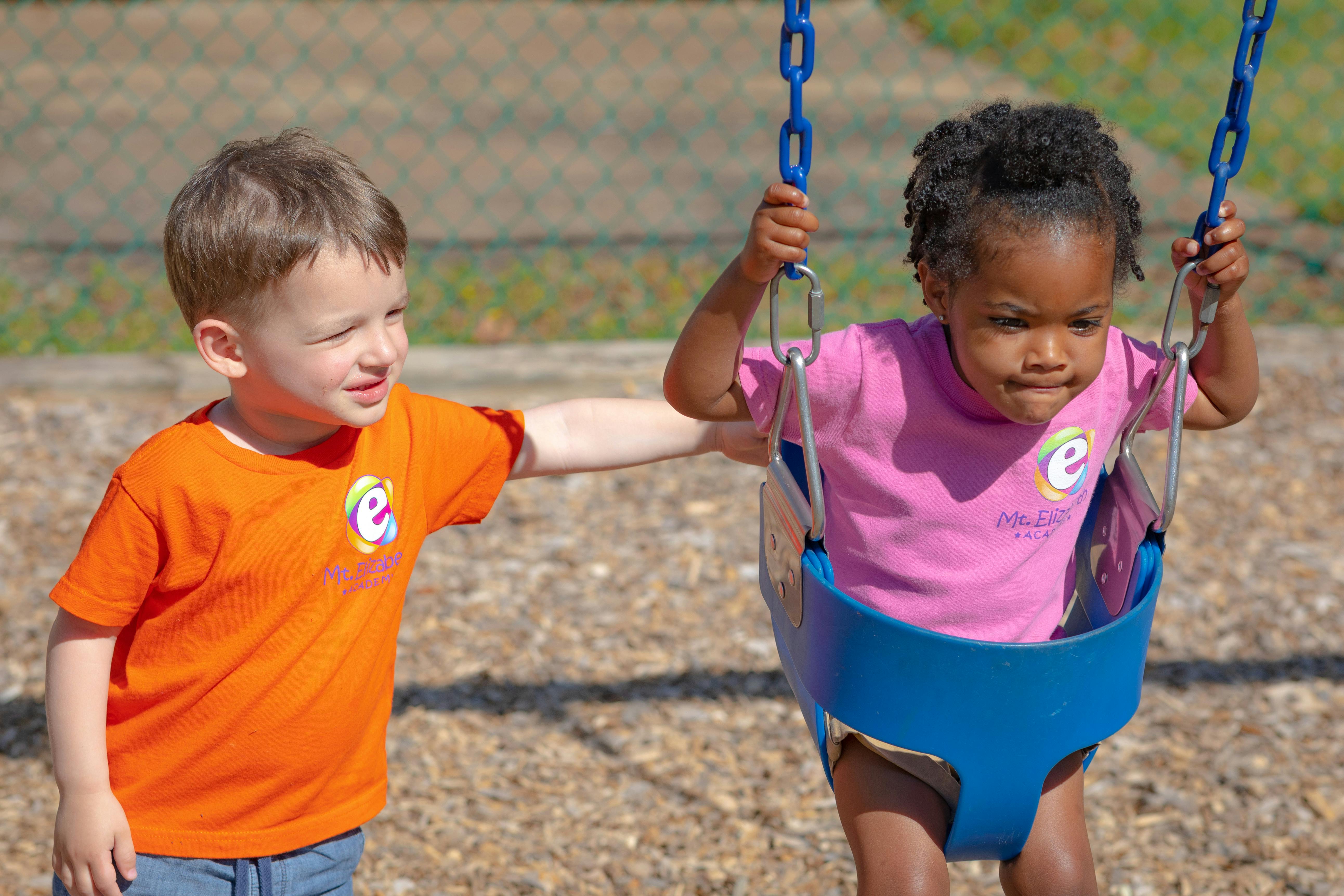 Child pushing another child on a swing