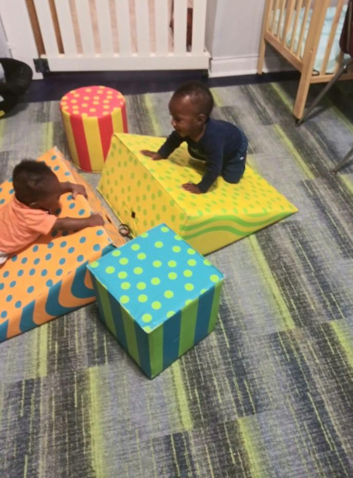 Two children playing on soft foam climbing blocks in a playroom