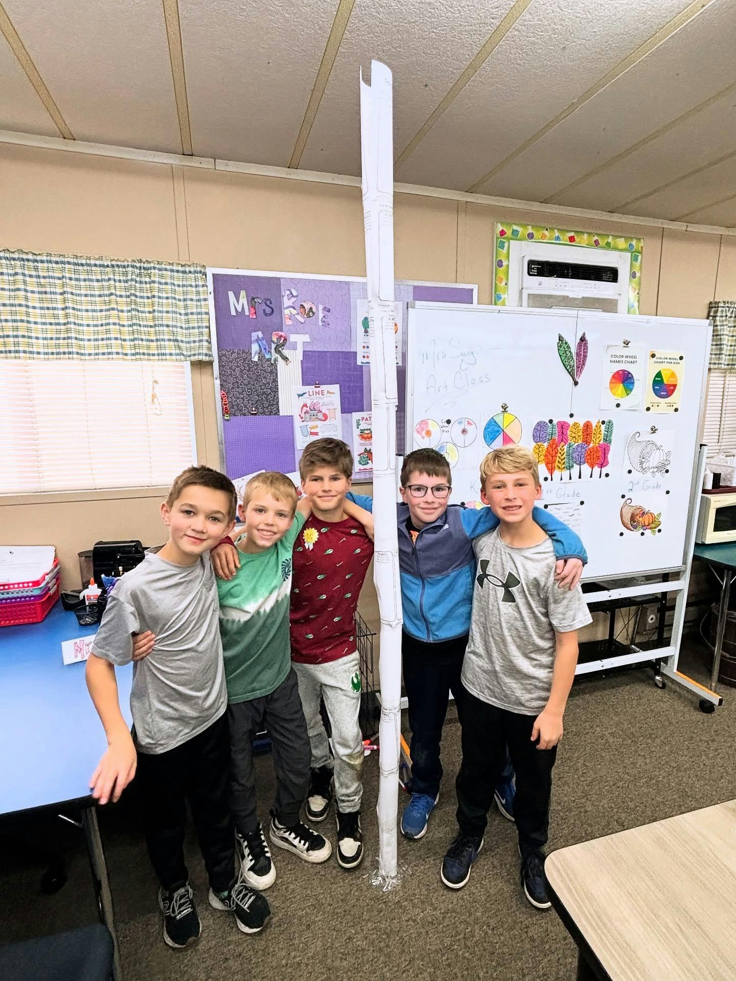 Five children standing together in a classroom