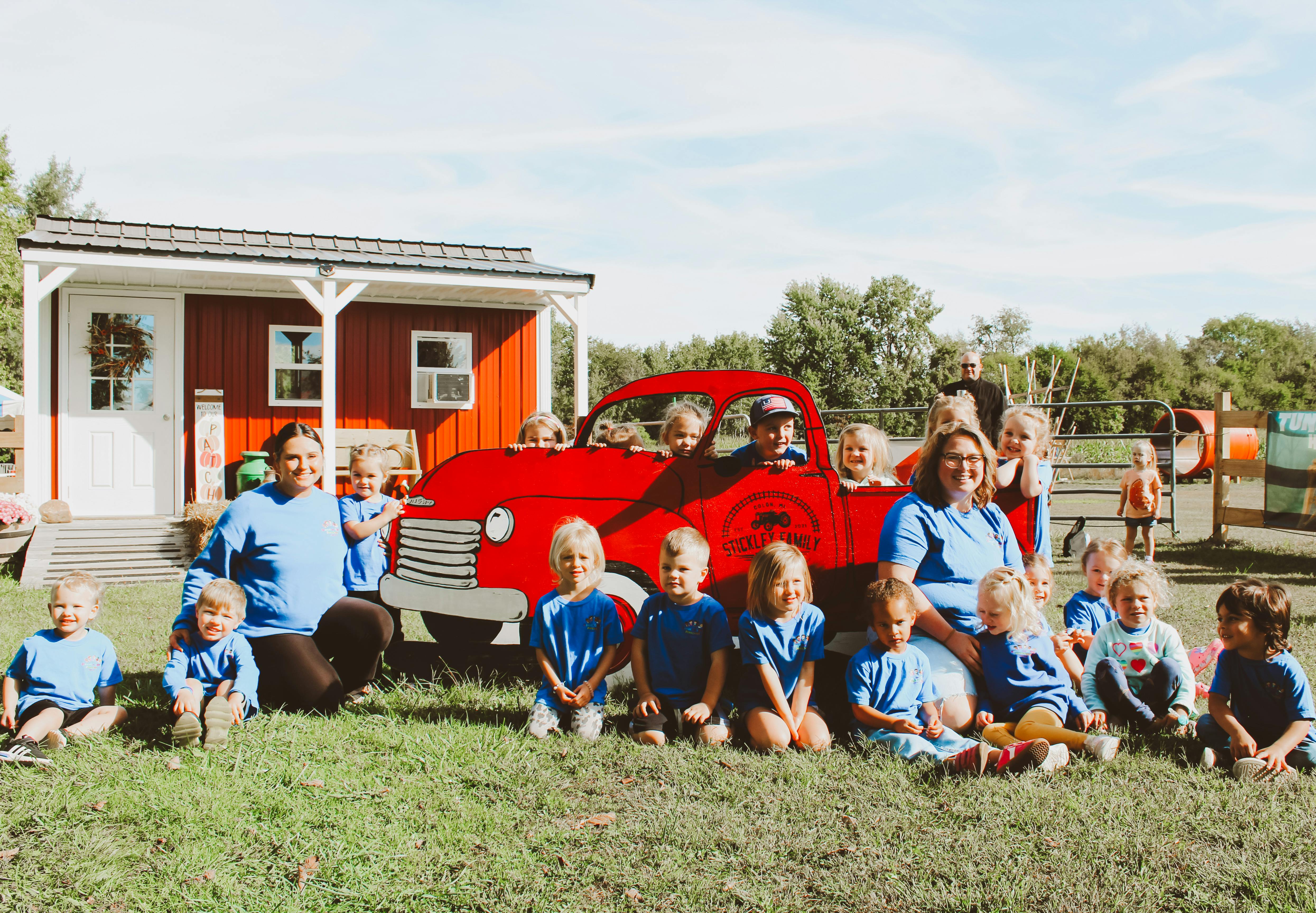 Group of children and adults sitting in front of a red truck cutout
