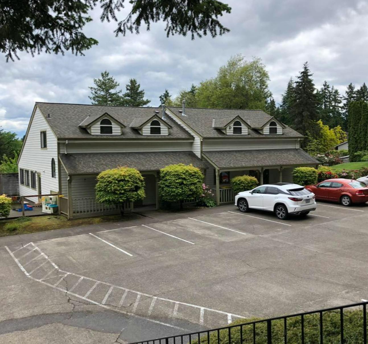 Building with dormer windows and a parking lot with cars