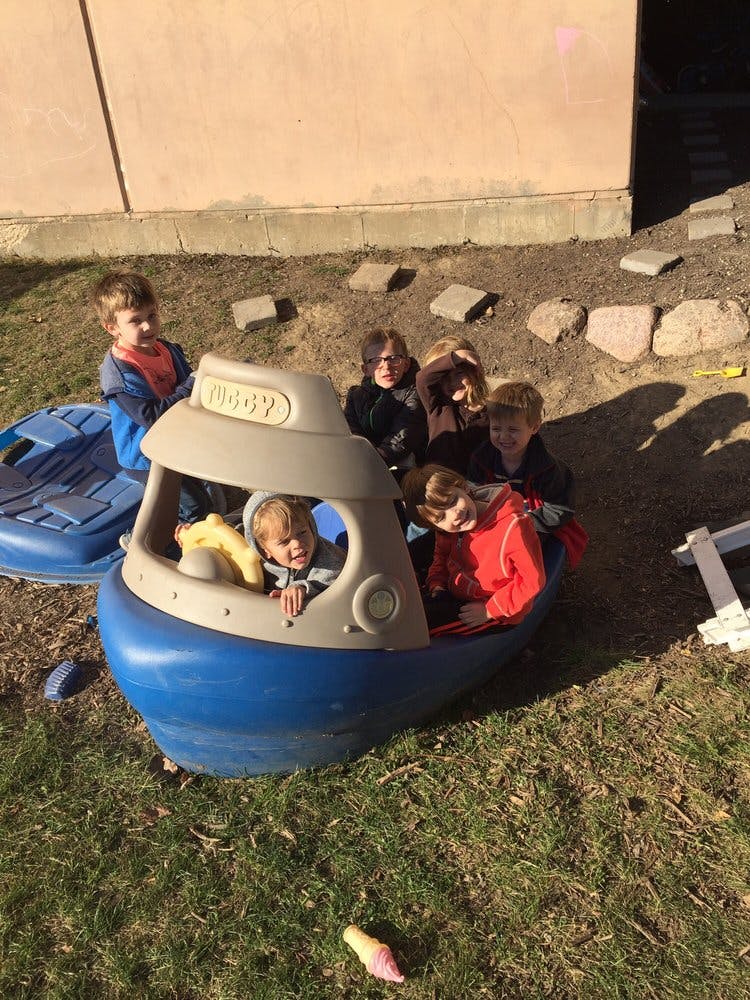 Children playing in a toy boat outdoors