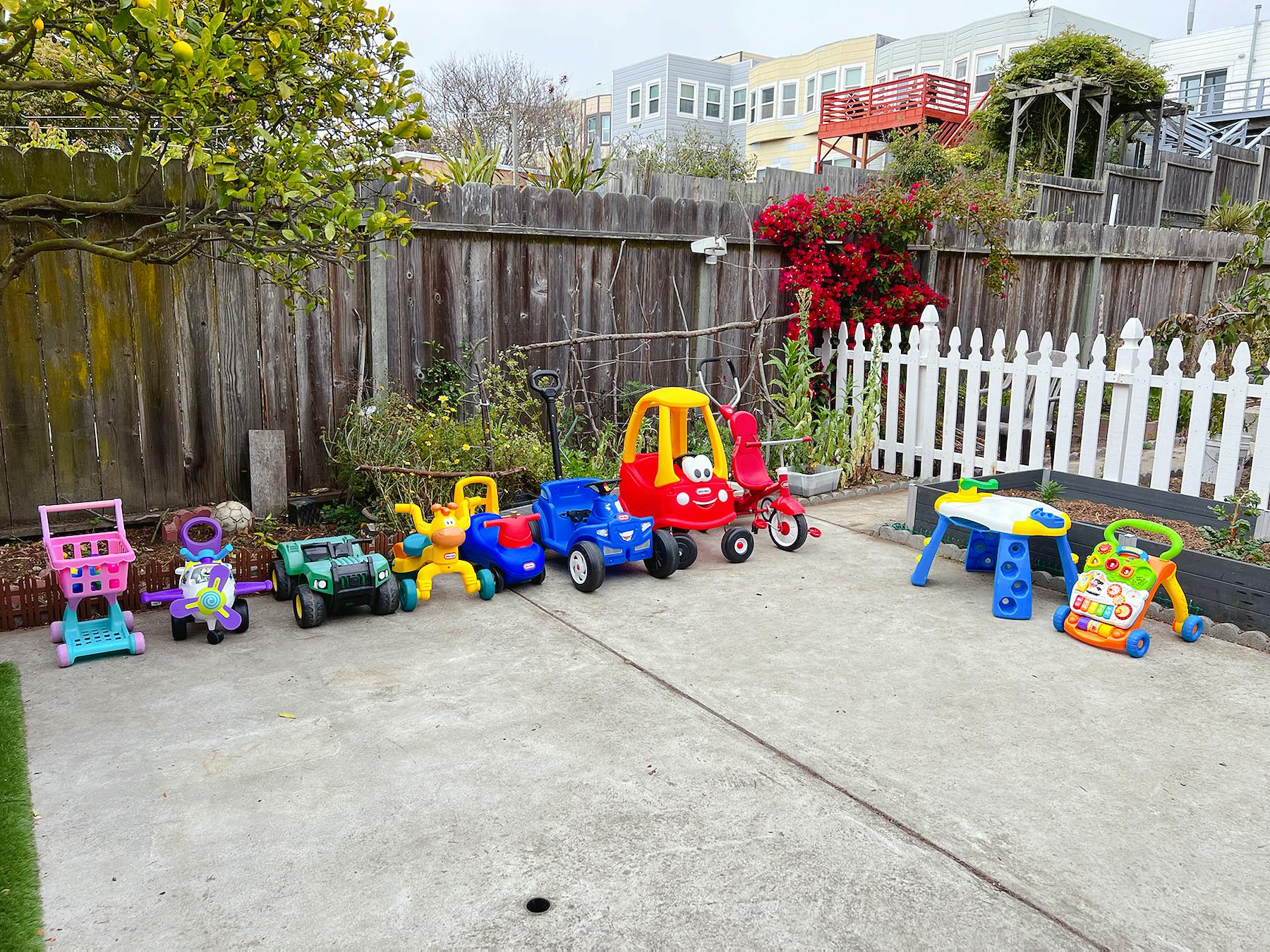 Assortment of colorful ride-on toys and walkers on a paved surface