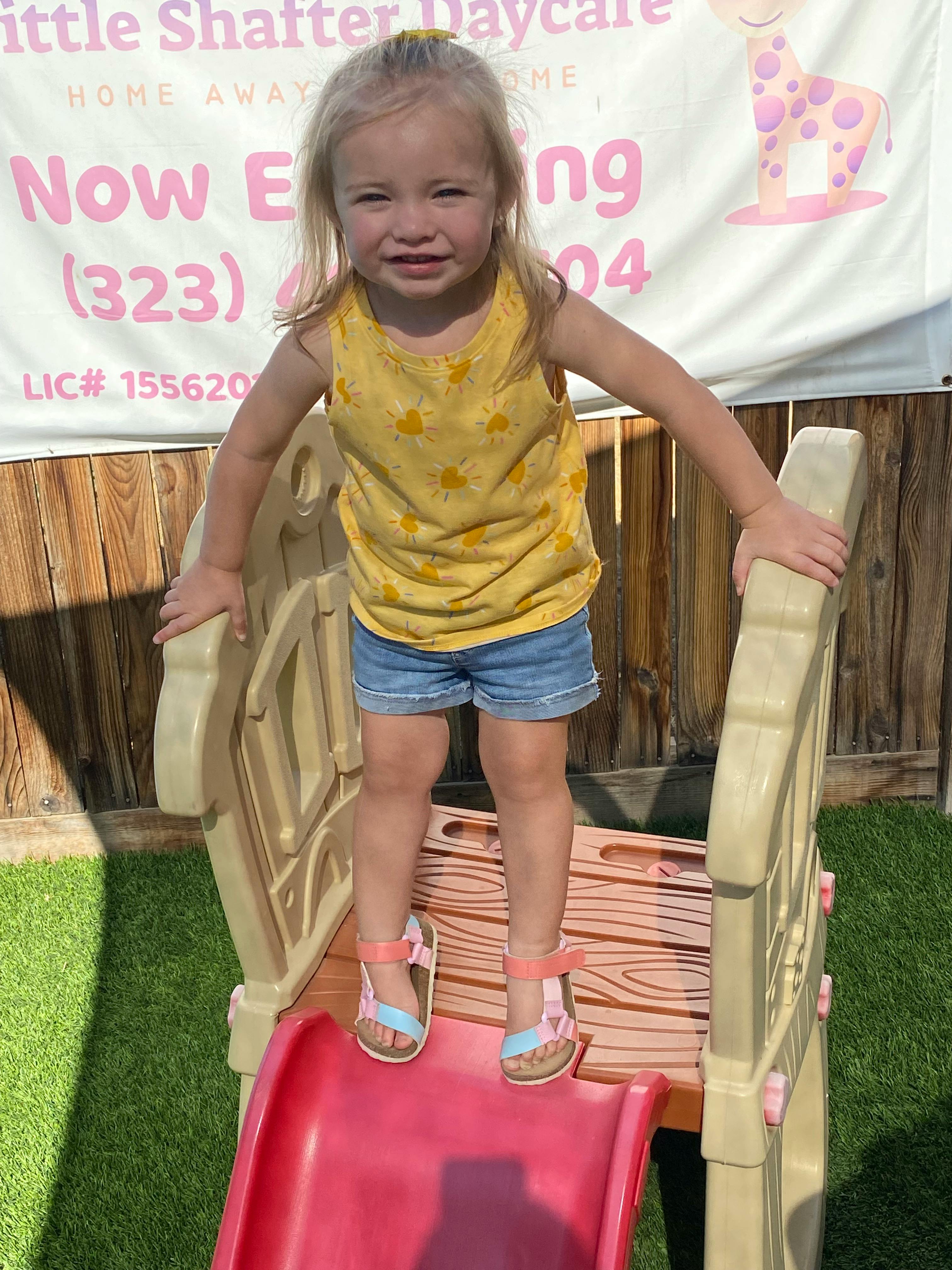 Child standing on top of a small slide