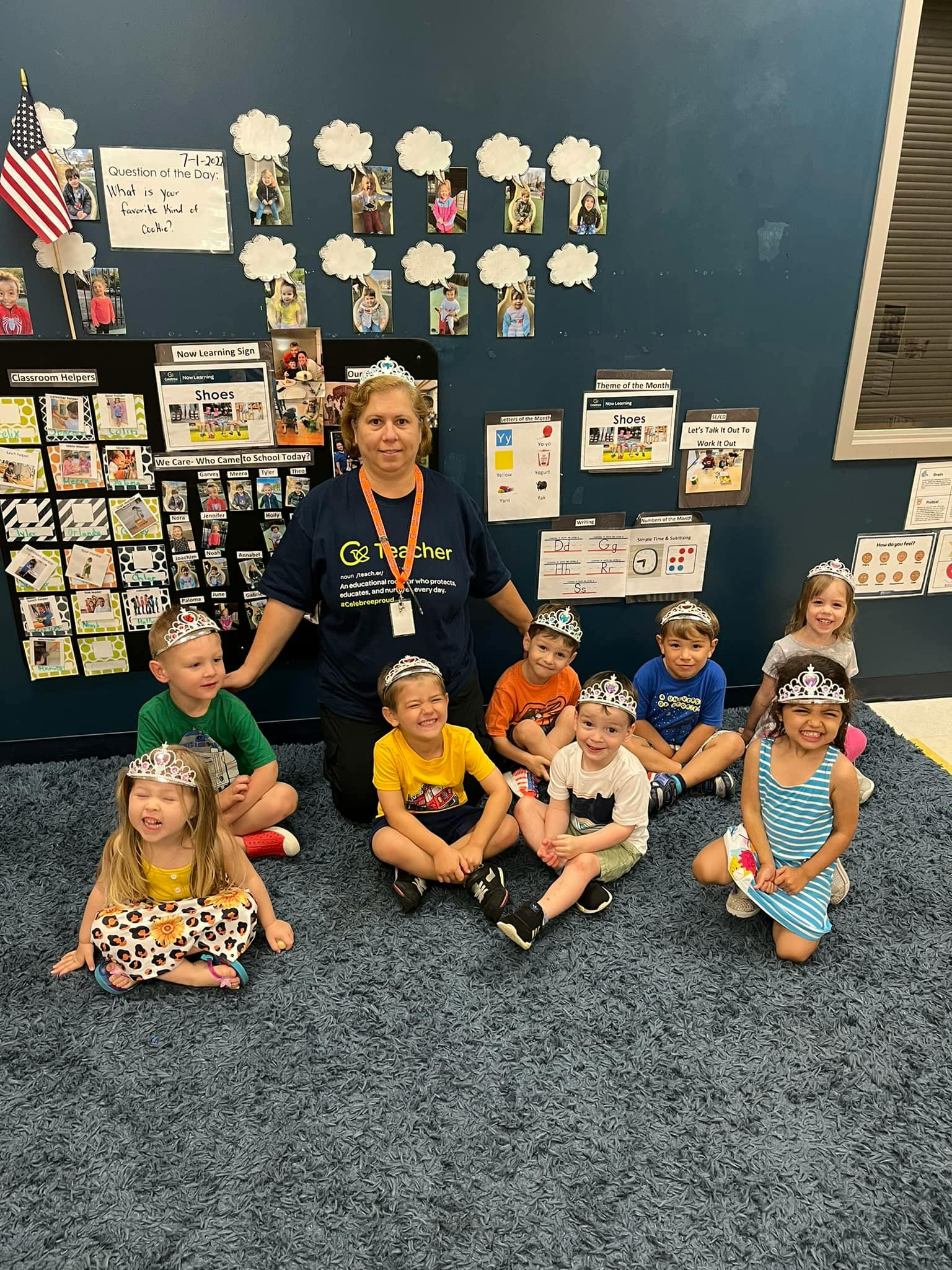 Adult and children wearing crowns sitting on a rug in a classroom