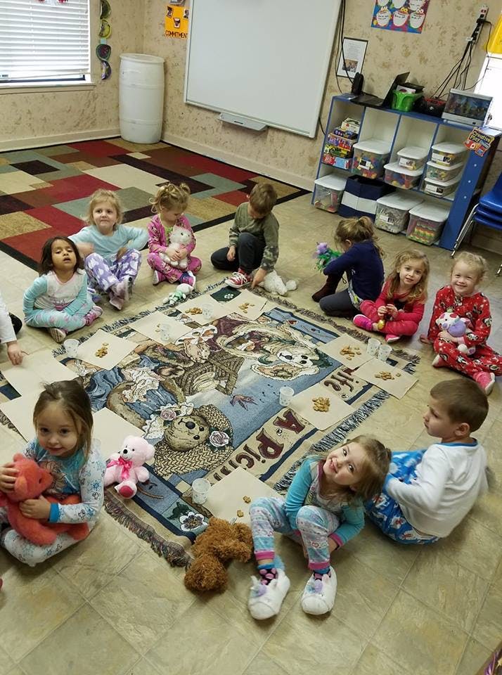 Children sitting on a blanket with stuffed animals