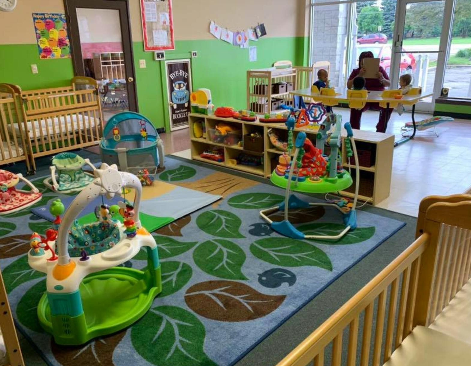 Daycare room with cribs, play mats, and activity centers