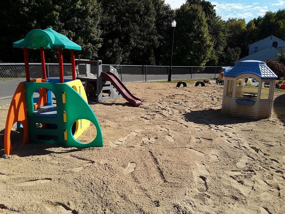 Playground with colorful play structure, slide, and small playhouse in sand