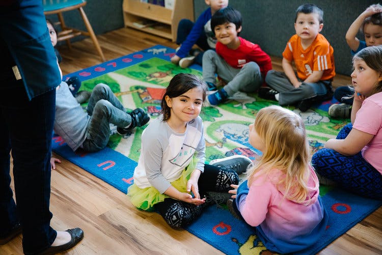 Children sitting on a rug in a classroom