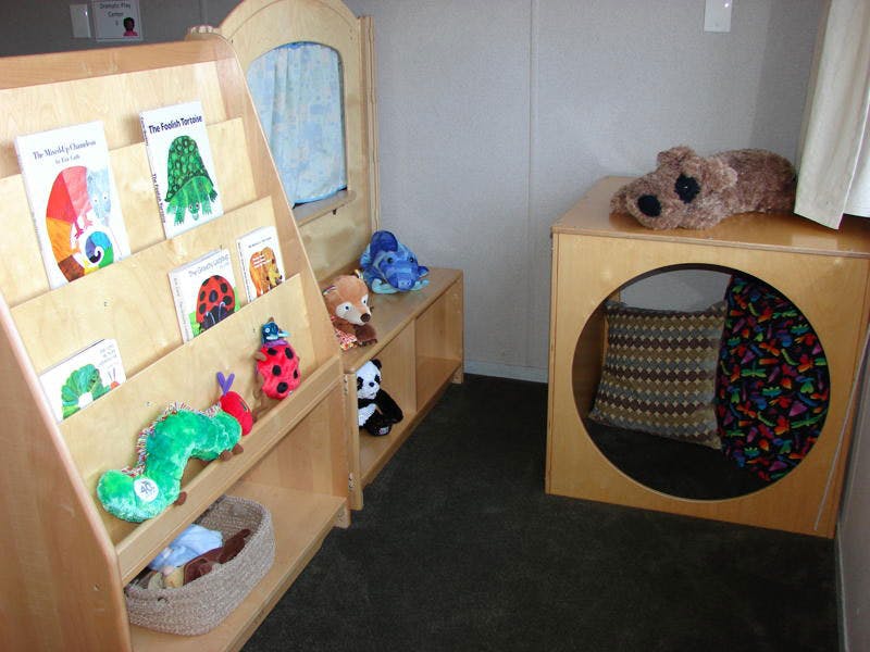 Children's reading nook with books, stuffed animals, and a cozy cubby
