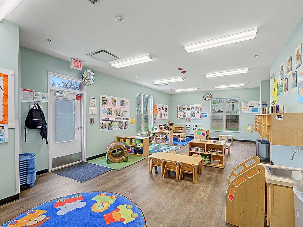 An empty preschool classroom with small tables and chairs