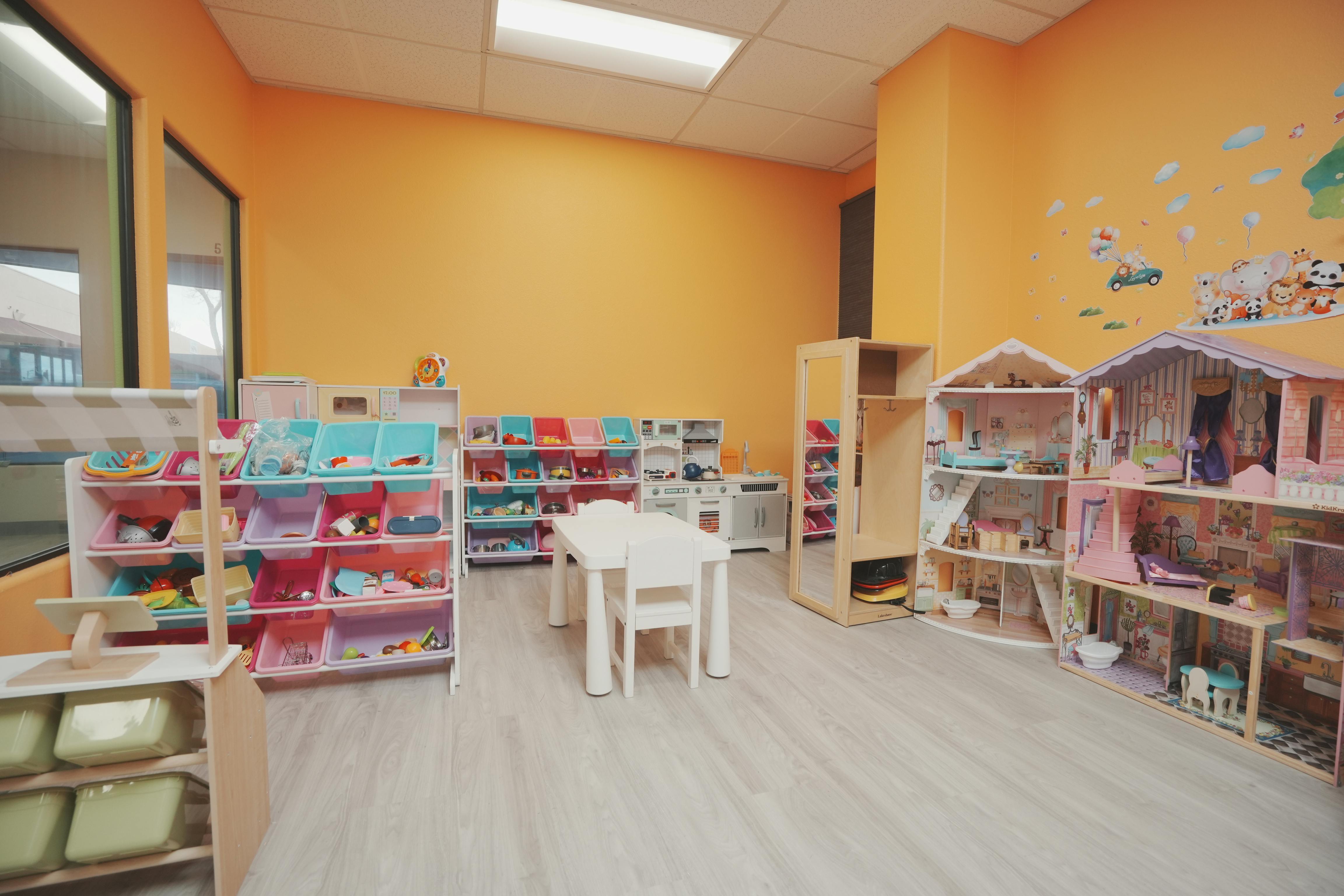 Playroom with shelves of toys, a small table and chairs, and dollhouses