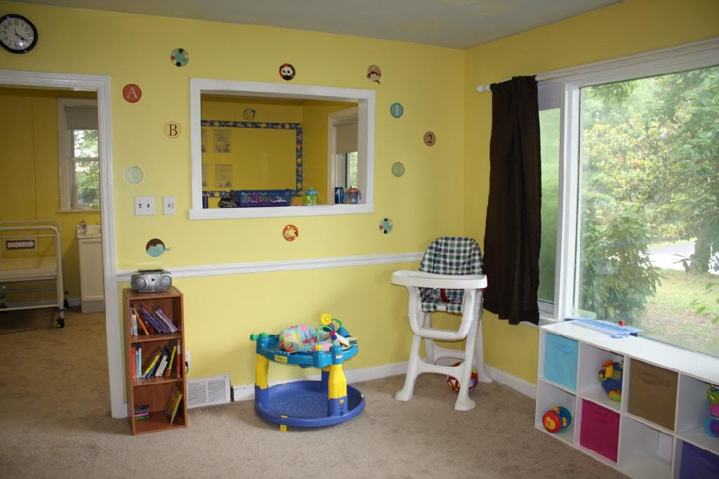 Child's room with yellow walls, high chair, and toys